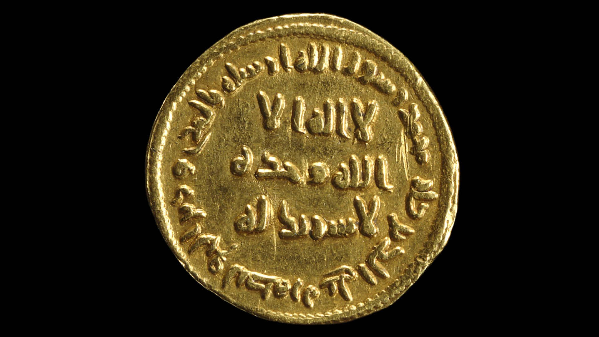 古代伊斯蘭黃金幣 壁紙 — 一枚刻有阿拉伯文字的古代金幣特寫，背景為純黑色。