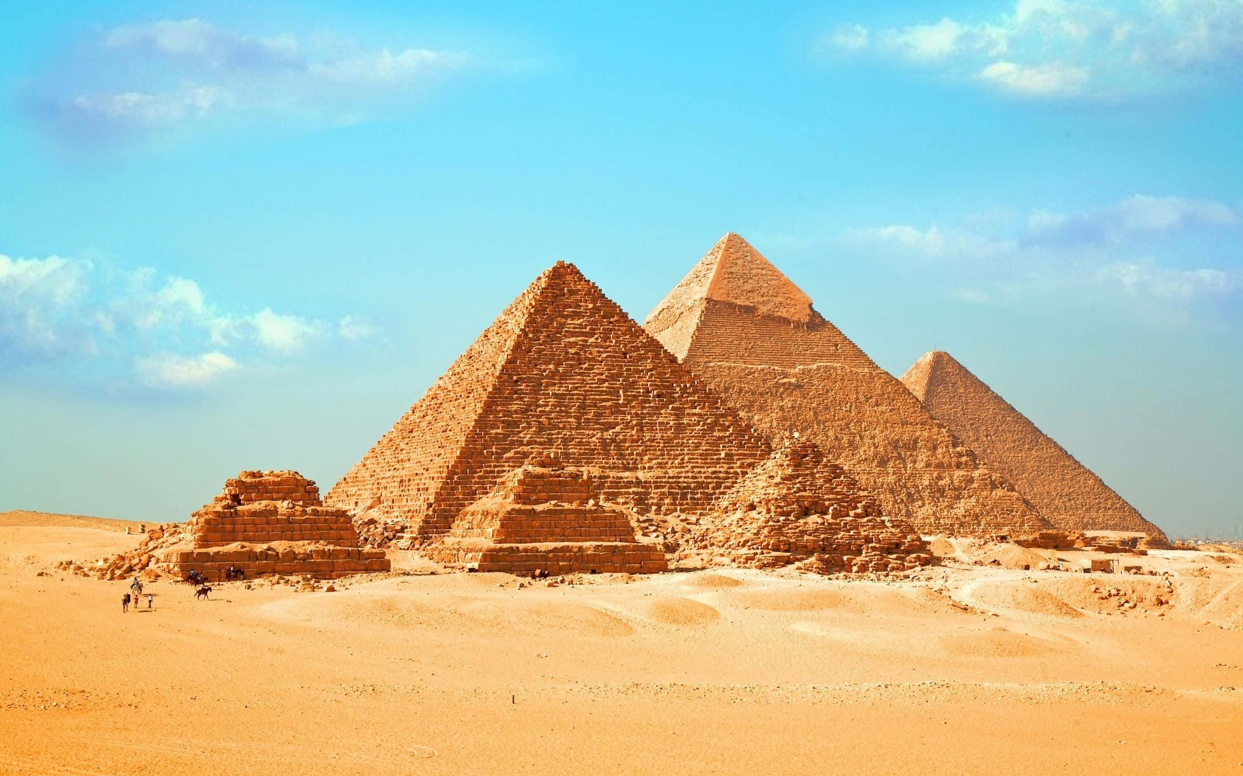 Egypt 桌布 壁紙 — 古埃及金字塔在藍天白雲下從金色沙漠中雄偉地崛起。