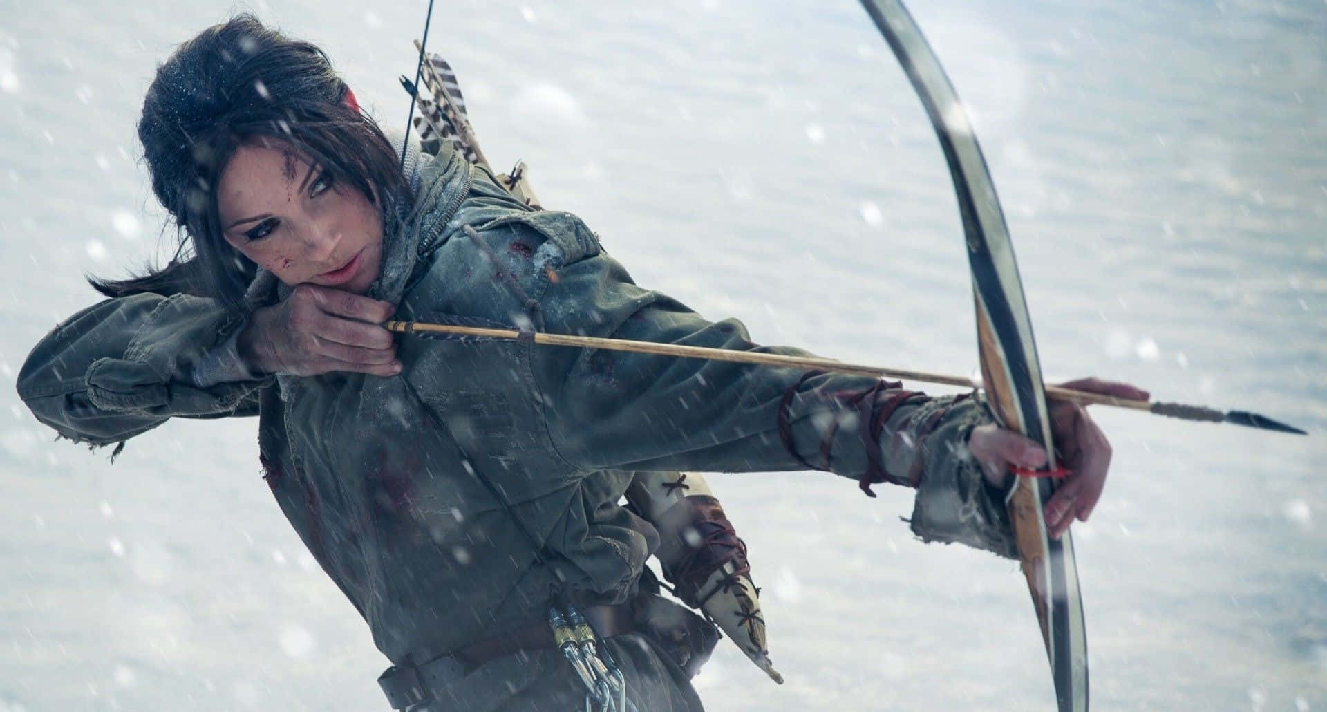 《古墓麗影：崛起》雪中弓箭手蘿拉·克羅夫特背景 1920x1080 壁紙 — 一位決心的弓箭手穿著風化的裝備，在嚴冬的雪景中拉弓，雪花飄落。