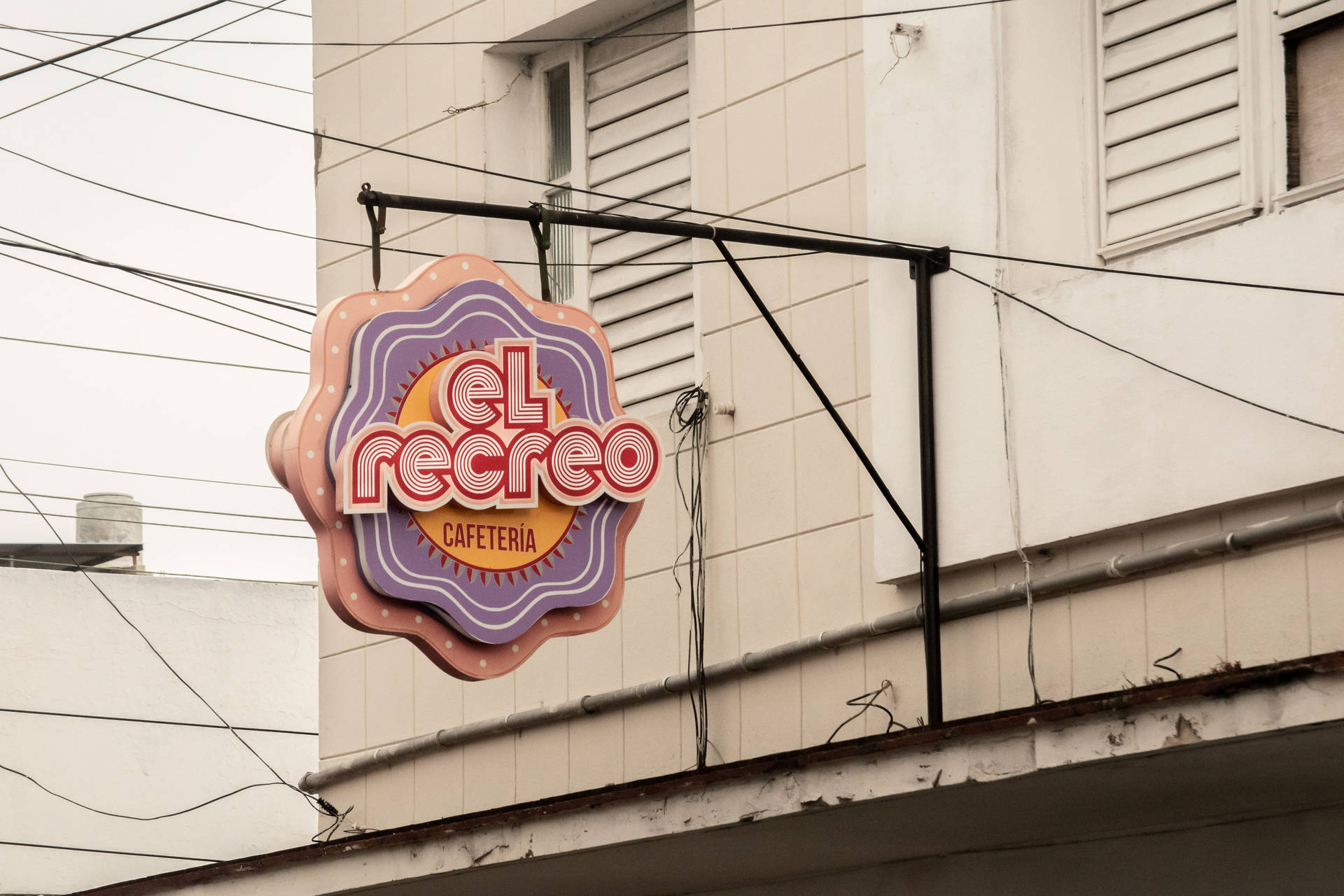 寫有el recreo的復古咖啡館招牌安裝在一個有纏繞電線的建築物上。