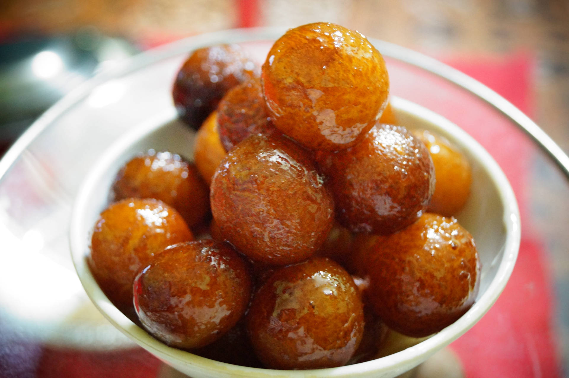 一碗浸滿糖漿的 gulab jamun 甜點，帶有閃閃發光的糖衣。