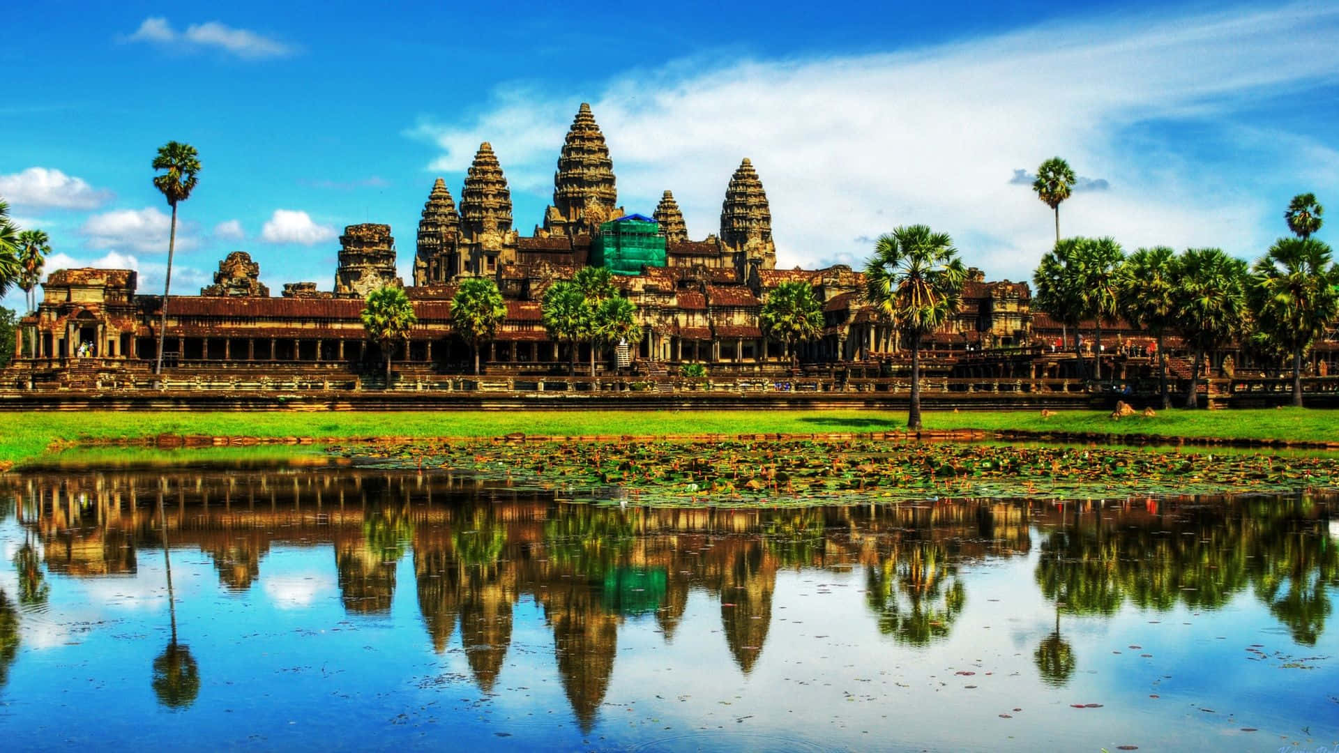 Thailand 桌布 壁紙 — 古老的吳哥窟寺廟群在平靜的池塘中完美倒映，上方是帶有散雲的明亮藍天。