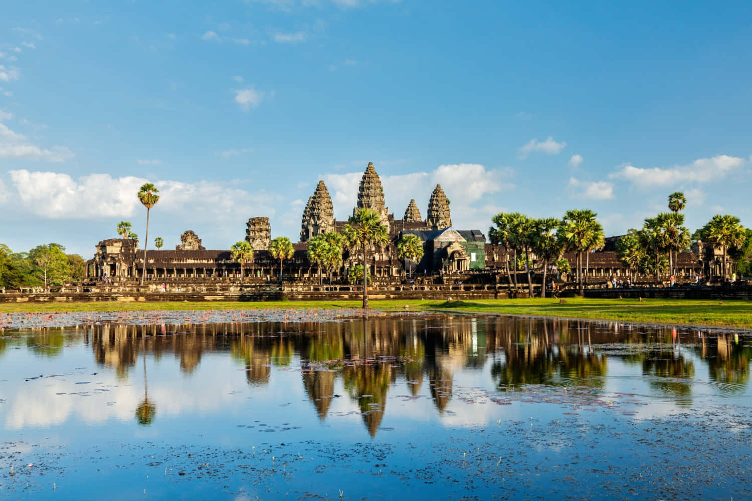 Asia 桌布 壁紙 — 古老的吳哥窟寺廟群在晴朗藍天和散雲下，完美倒映在平靜的池塘中。