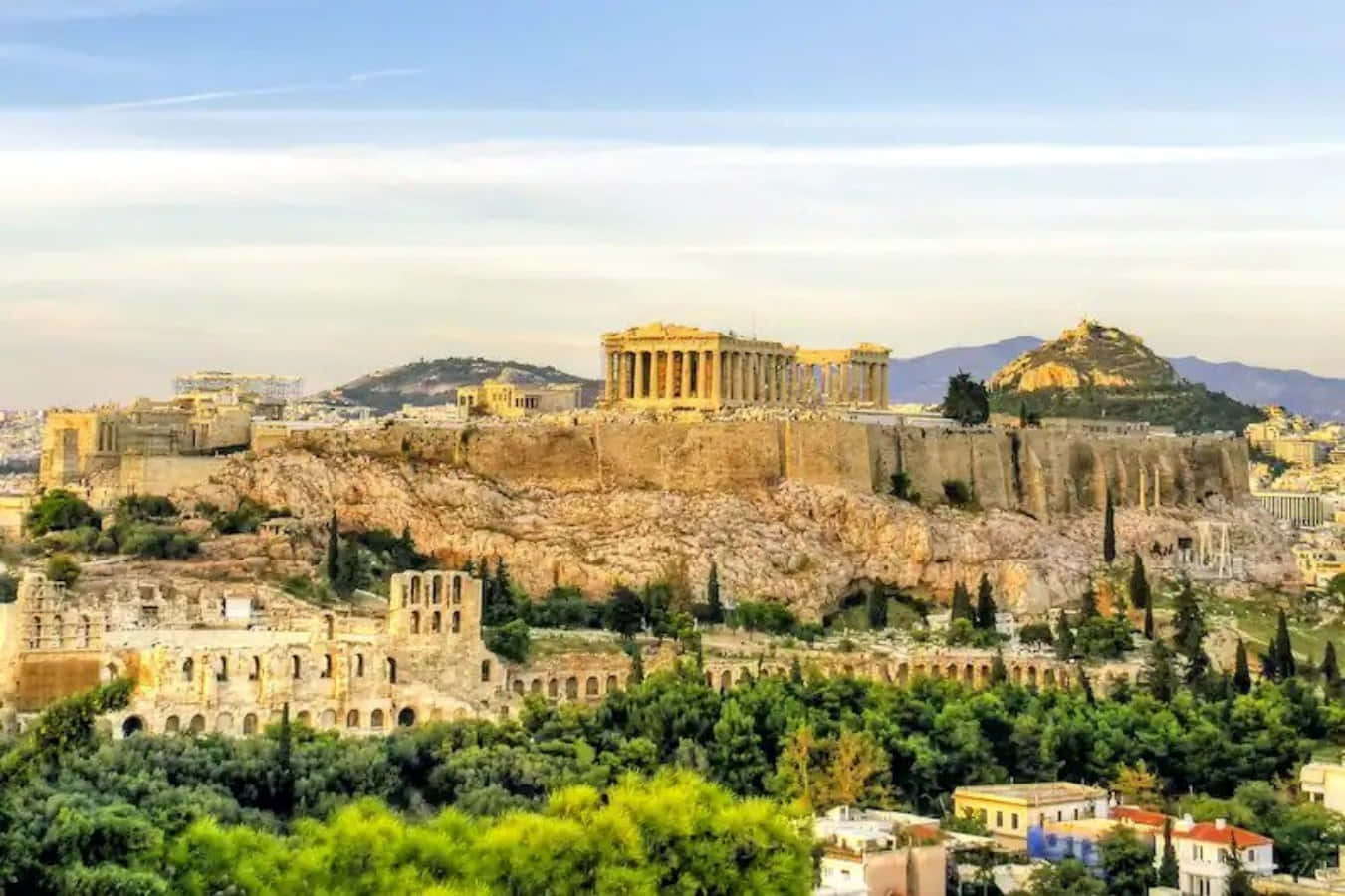 greek 桌布 壁紙 — 古老的帕德嫩神廟雄偉地矗立在雅典衛城山頂上，周圍環繞著茂密的綠植和現代城市景觀，在清澈的藍天下。