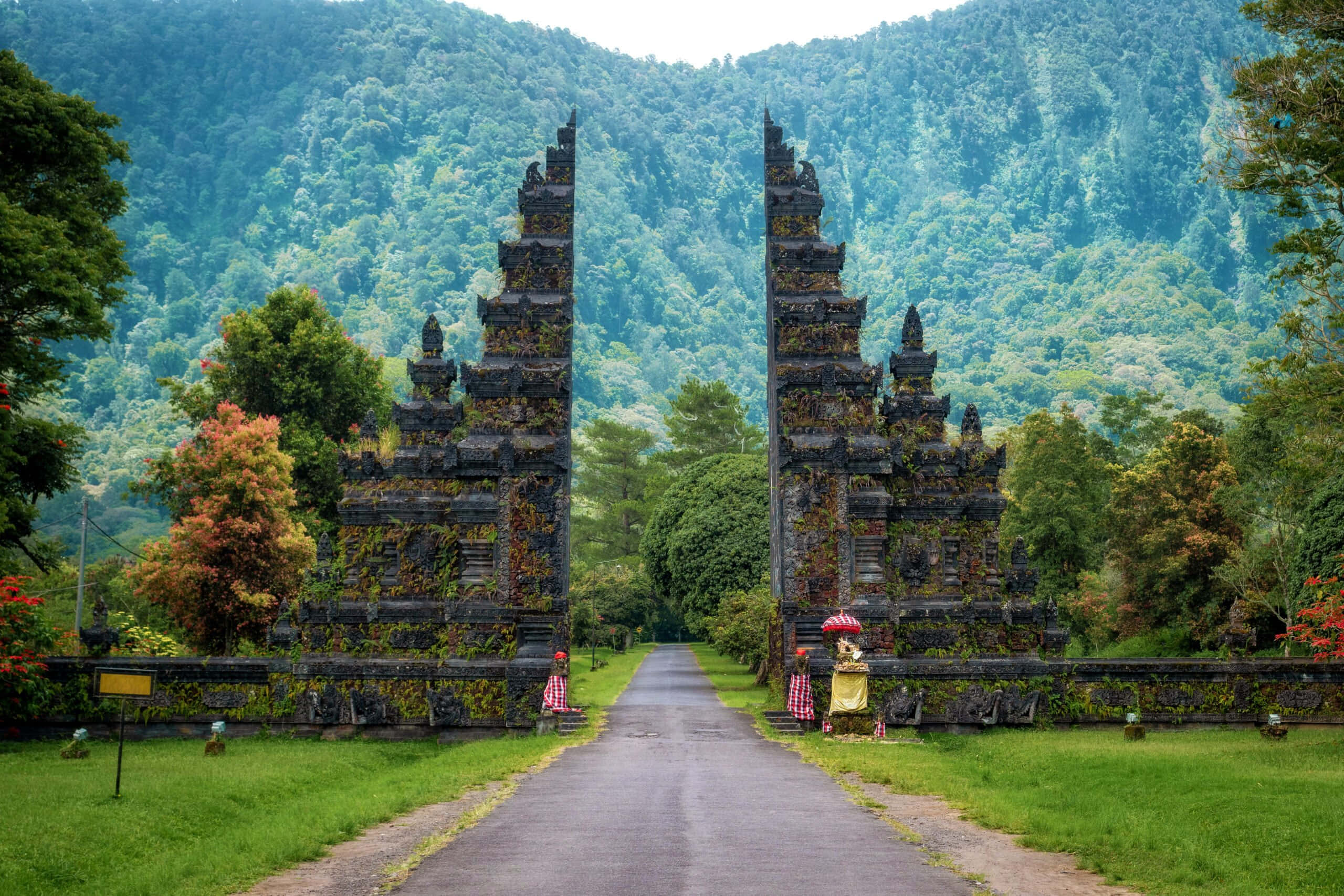 Indonesia 桌布 壁紙 — 古老的石門在鬱鬱蔥蔥的綠色山谷入口處雄偉地聳立，四周環繞著森林覆蓋的山脈。