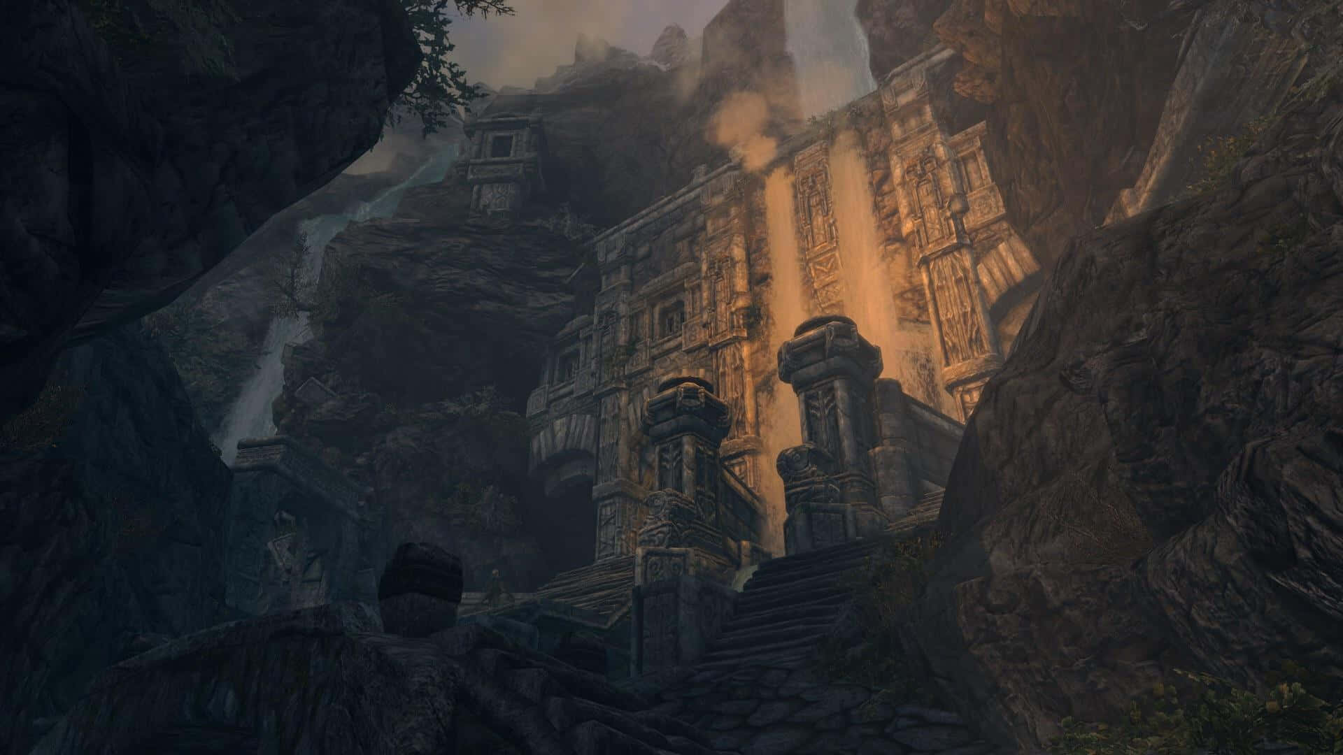 Skyrim Markarth 桌布 壁紙 — 古老石廟雕刻在霧氣繚繞的山崖上，沐浴在瀑布傾瀉而下的溫暖金色光芒中。