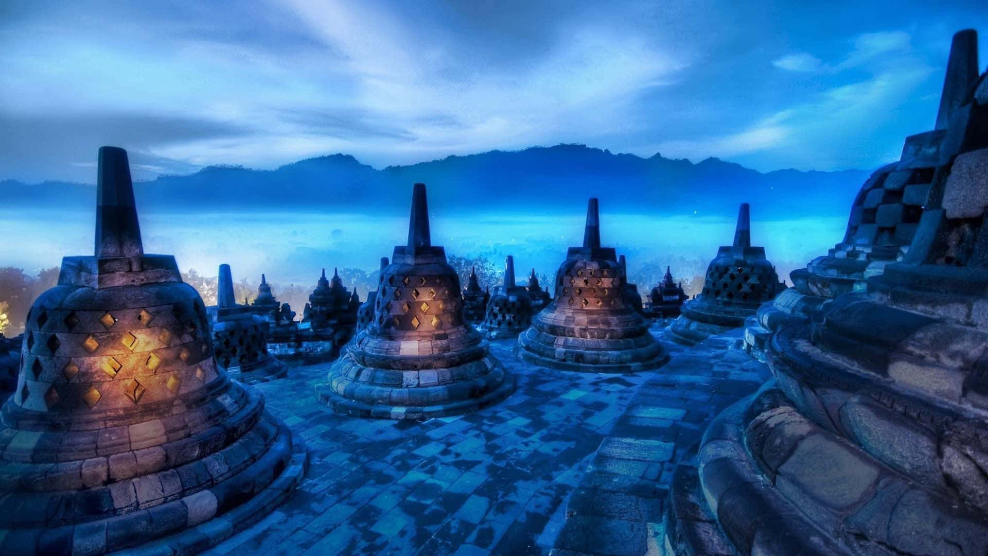 3d Travel 桌布 壁紙 — 古老石製佛塔在涼爽的藍色暮色天空和遠山的襯托下溫暖地發光。