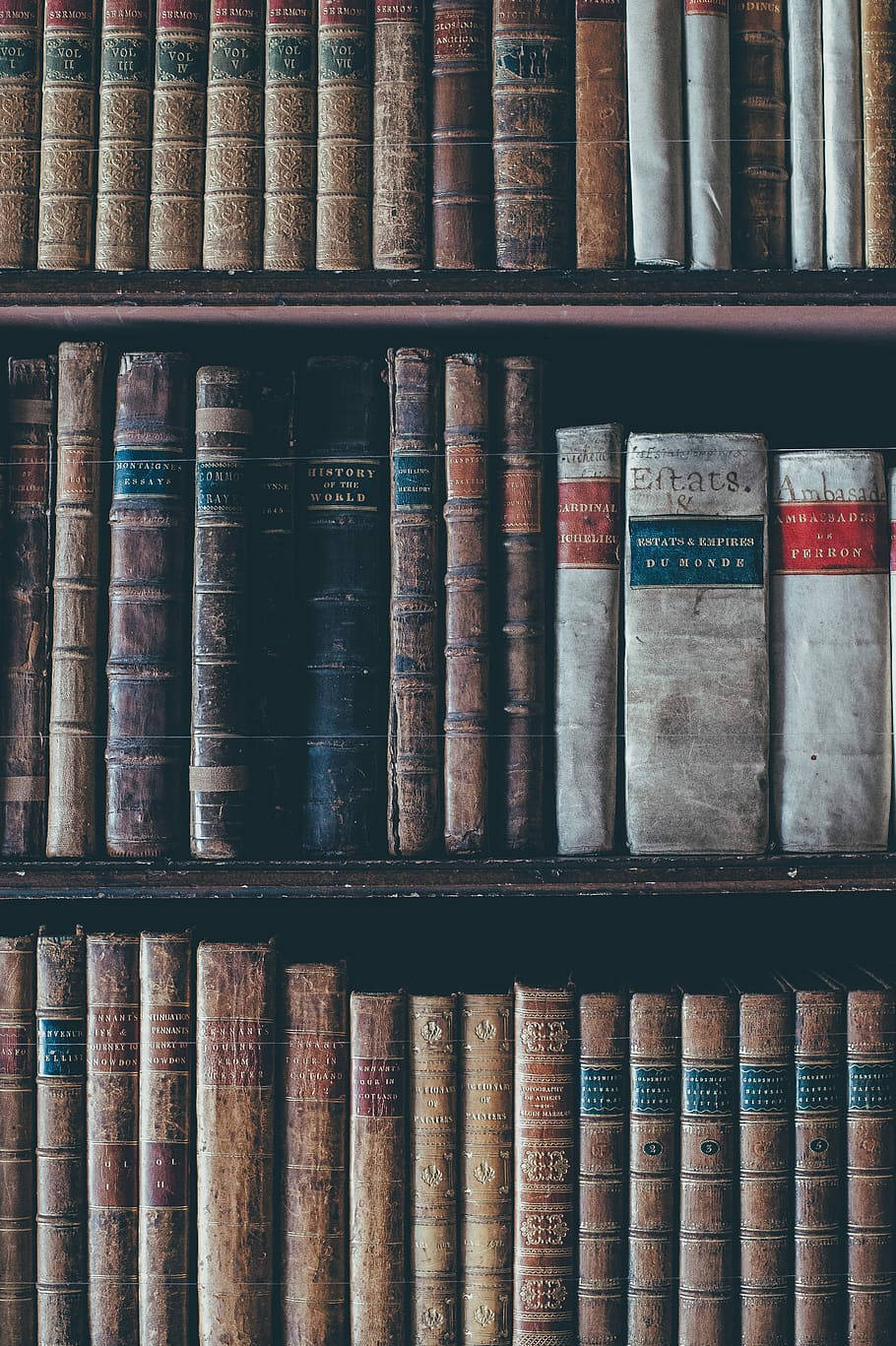 古舊書架上的歷史書籍 壁紙 — 一排排陳舊的皮革和布面裝訂的書籍填滿了復古圖書館的深色木質書架。