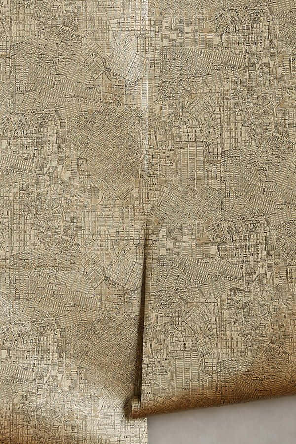 古董地圖金屬質感背景 壁紙 — 米色紋理牆紙的特寫，帶有複雜的壓花城市地圖圖案和捲邊。