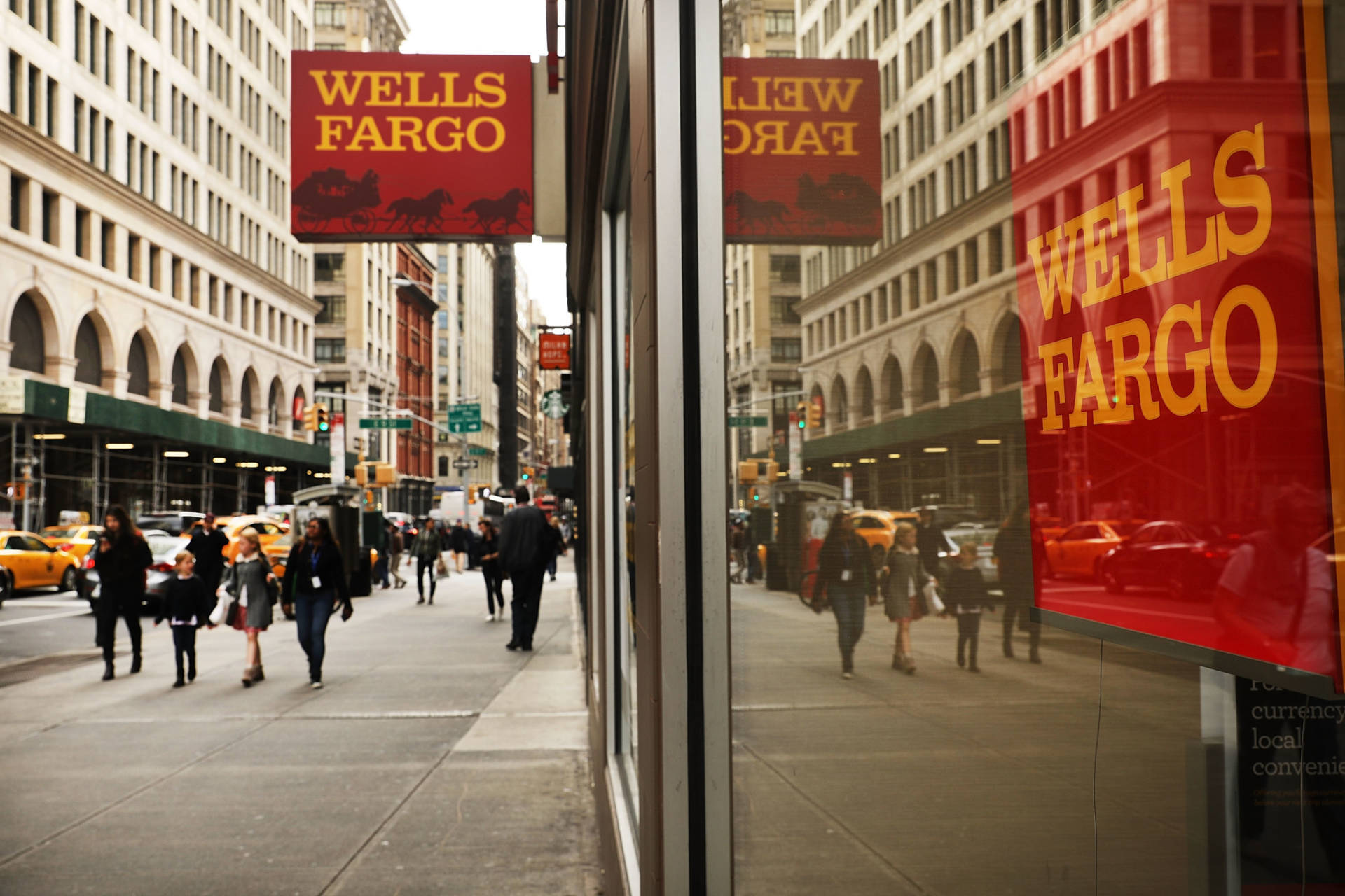 繁忙的城市街道，玻璃窗反射出 Wells Fargo 銀行標誌和黃色的士。