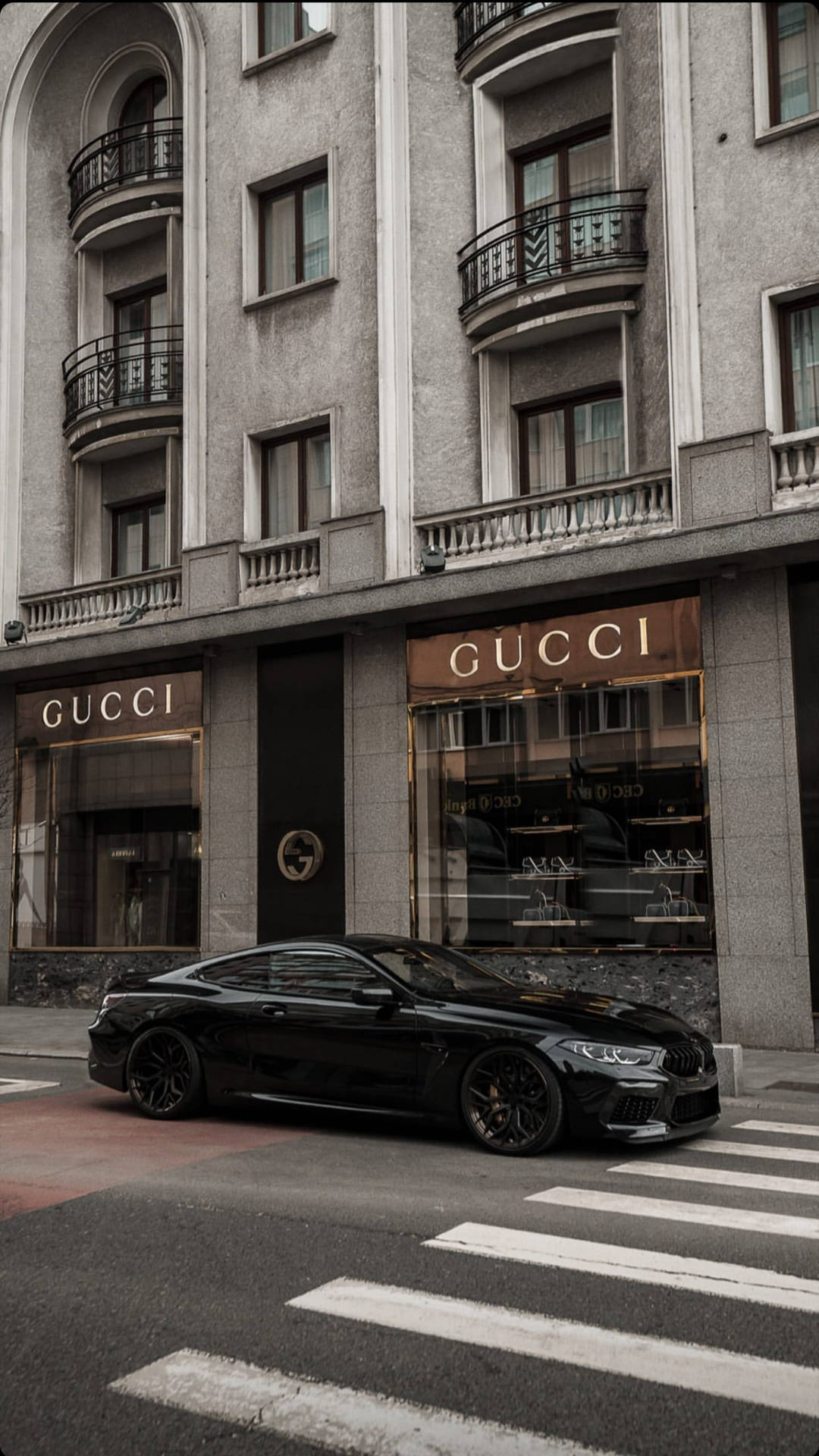 黑色豪華跑車停在城市街道上的Gucci商店前。