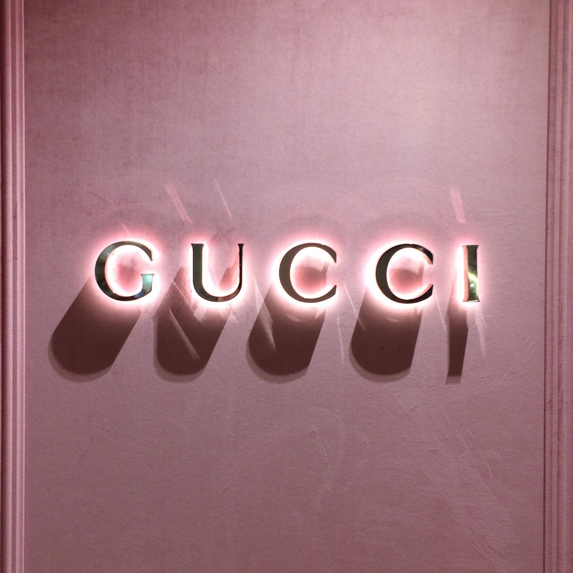 粉紅色發光GUCCI標誌在帶有紋理的牆壁上投射柔和陰影。