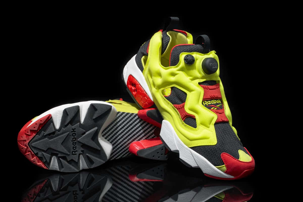只接受卓越，不將就 壁紙 — 鮮豔的螢光黃、紅和黑色Reebok Pump運動鞋，在帶有反射表面的純黑背景上展示。