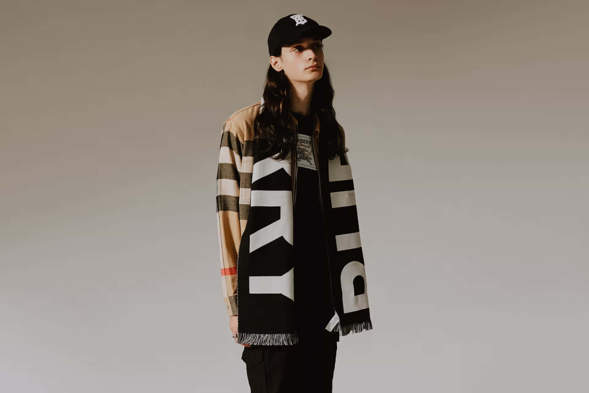 在工作室中穿著 Burberry 格紋外套和帶有字樣的大圍巾的人。
