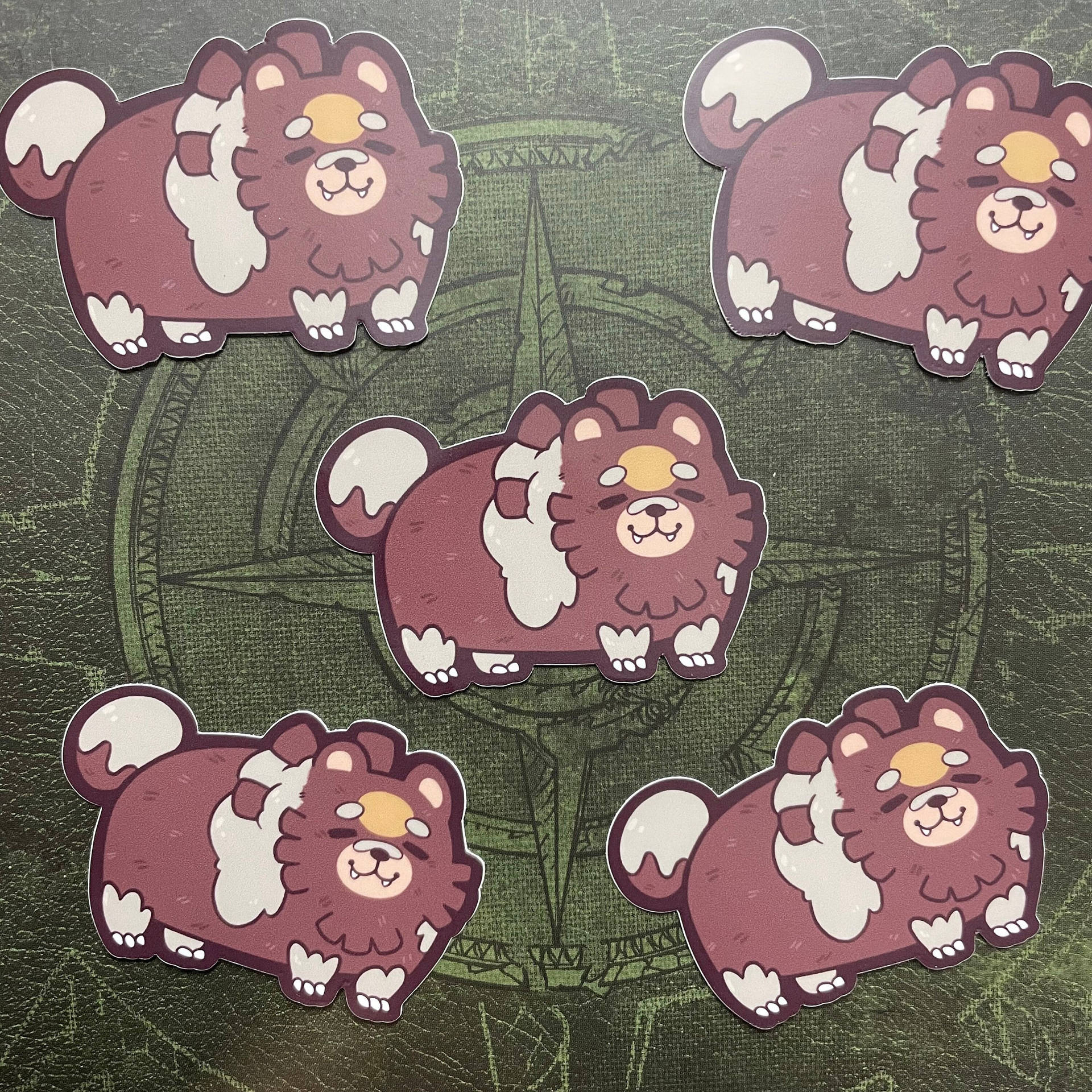 五個卡通鬆獅犬貼紙在綠色指南針玫瑰背景上。