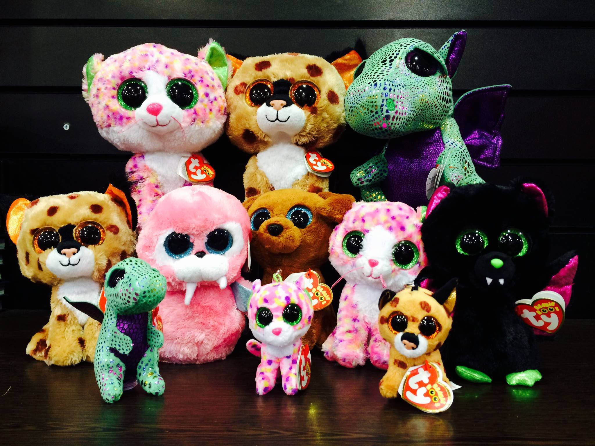 可愛Beanie Boos玩偶壁紙 壁紙 — 色彩繽紛的 Ty Beanie Boo 毛絨玩具系列，帶有閃爍眼睛和各種圖案，排列在深色木質表面上。