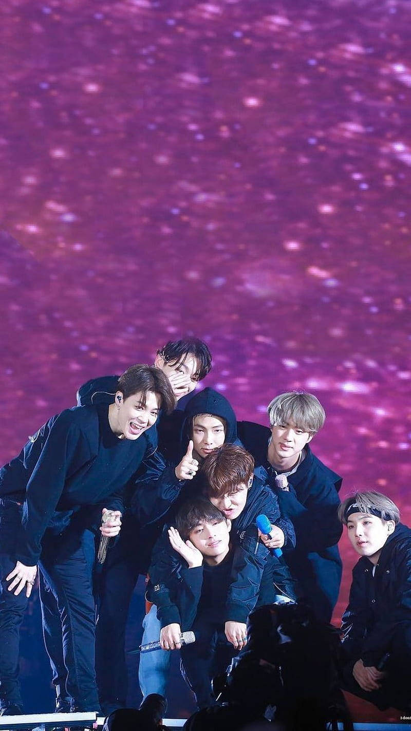 K-pop 組合在紫色星光下舞台上擺姿勢。