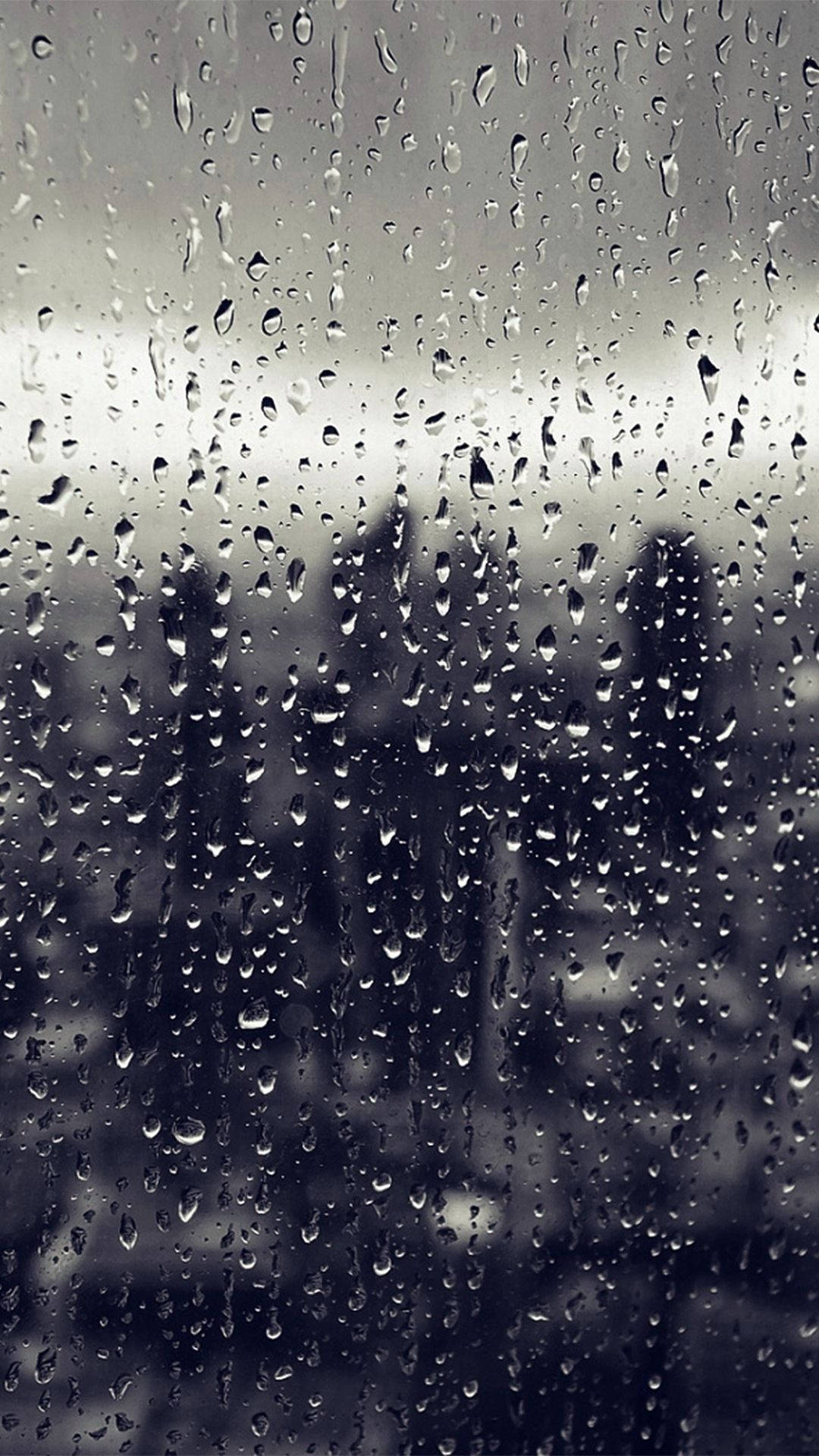 窗戶上的雨滴，呈現模糊的灰階城市景觀。