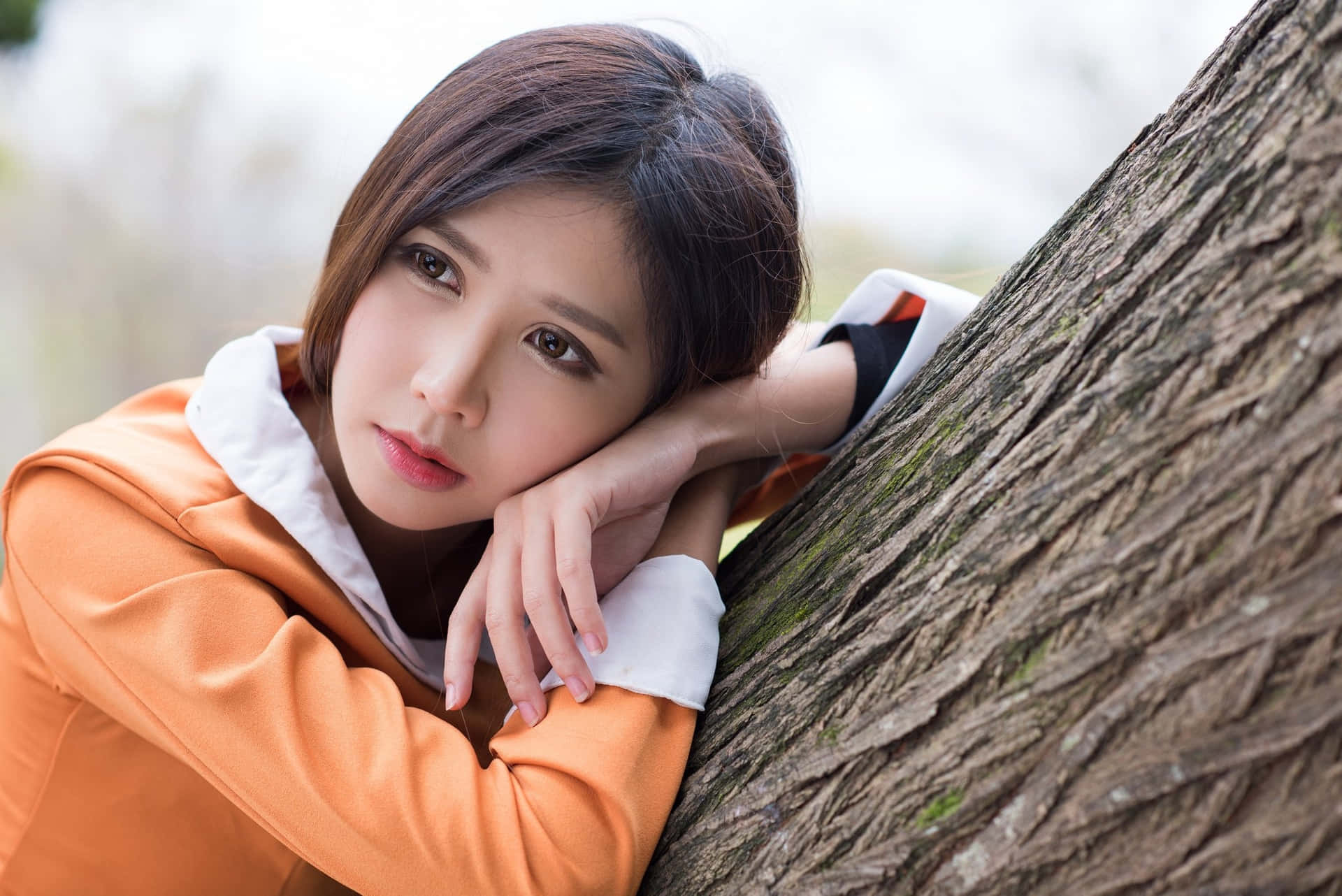 年輕女性在白天將頭靠在樹幹上休息。