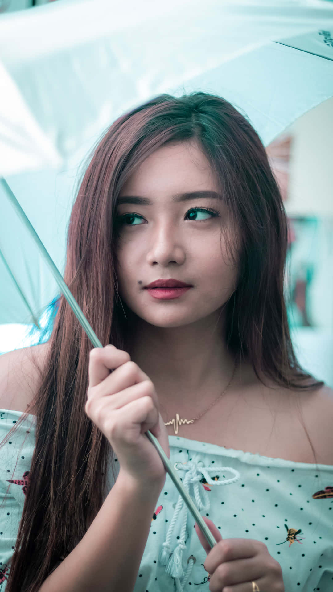 年輕女性手持藍色雨傘若有所思地望向一旁