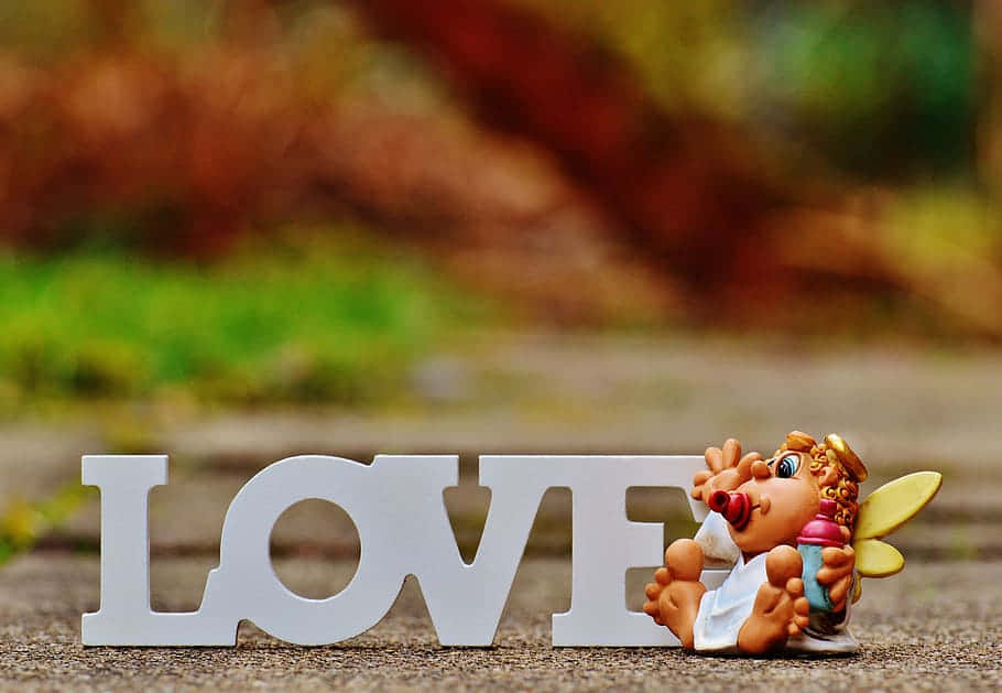 白色的LOVE字母，旁邊有一個小天使玩具在行人路上。