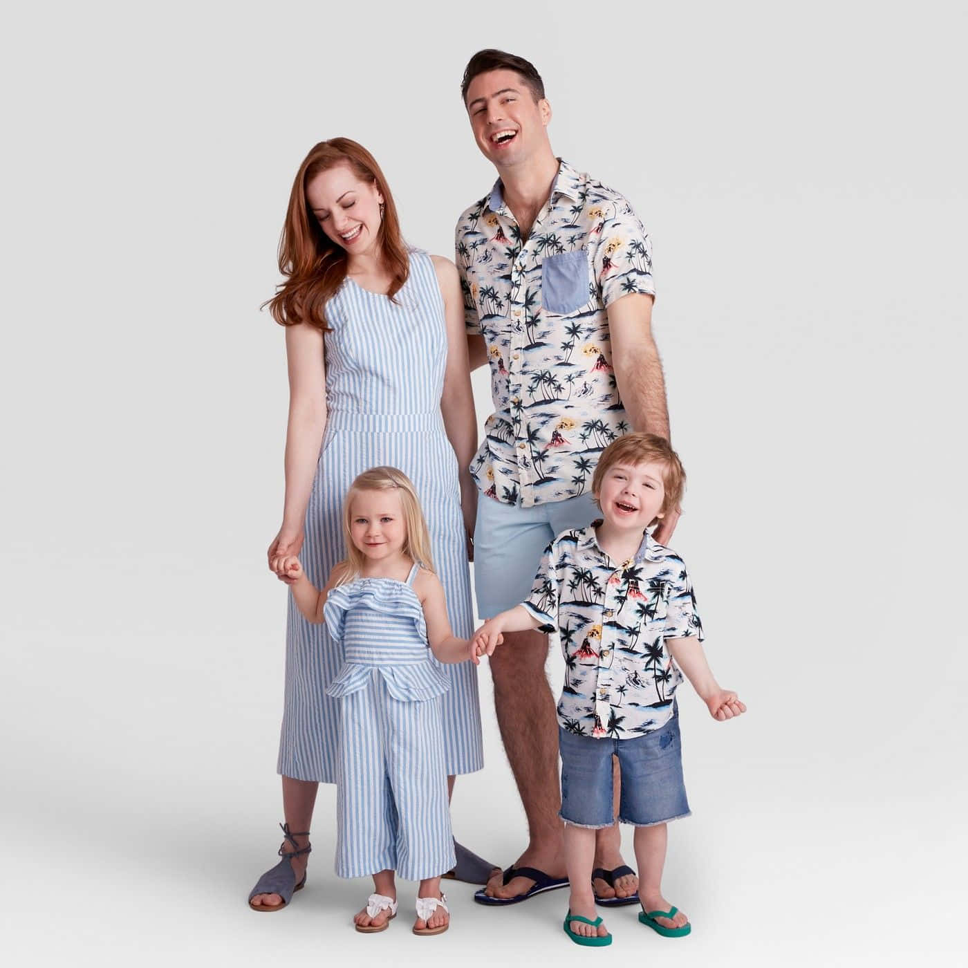 一個微笑的四口之家穿著相配的夏季服裝一起擺姿勢。