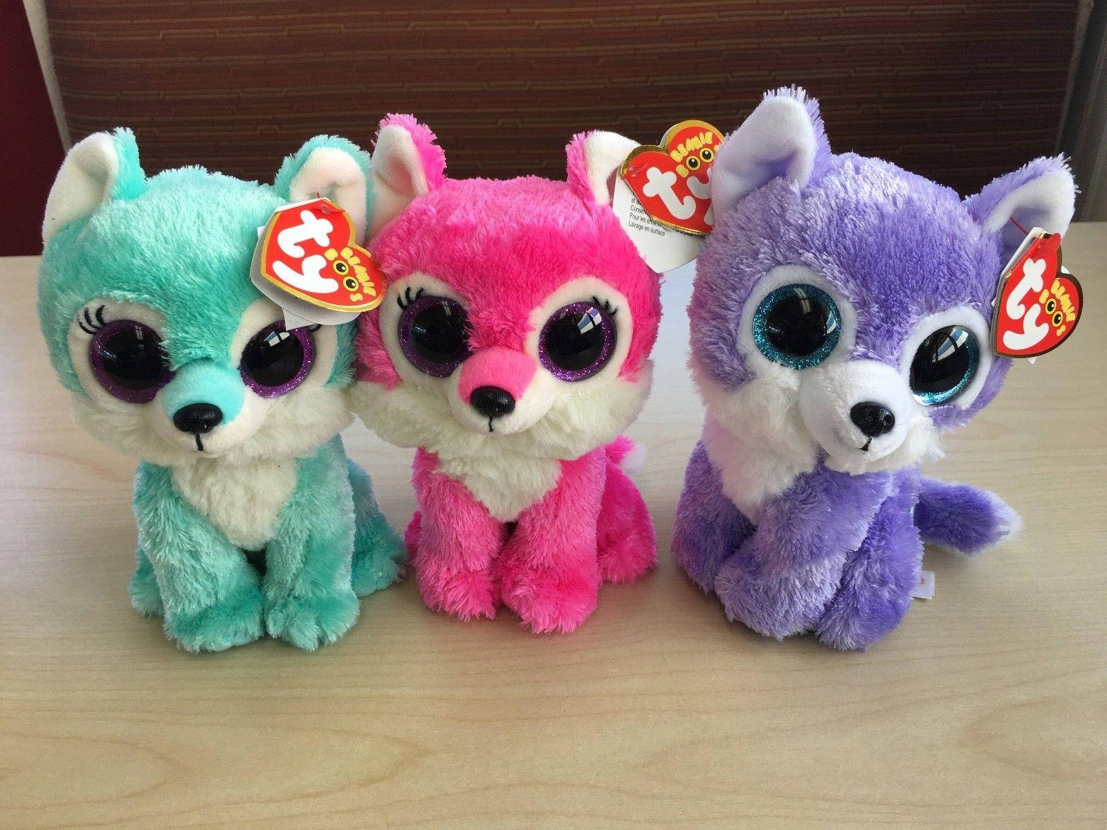 可愛小狗 Beanie Boos 壁紙 — 三隻色彩繽紛的Ty Beanie Boo毛絨狐狸，擁有超大的閃亮眼睛，並排坐在木質表面上。