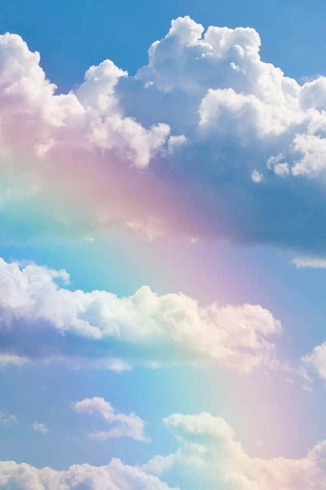 一道色彩繽紛的彩虹在清澈藍天中柔軟的白雲上拱起。