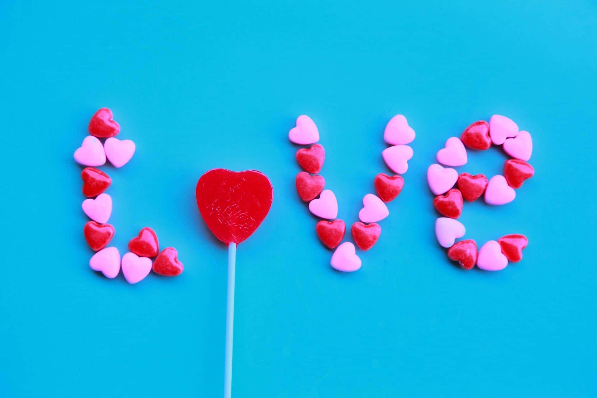 心形糖果用中間嘅紅色棒棒糖拼出 love。