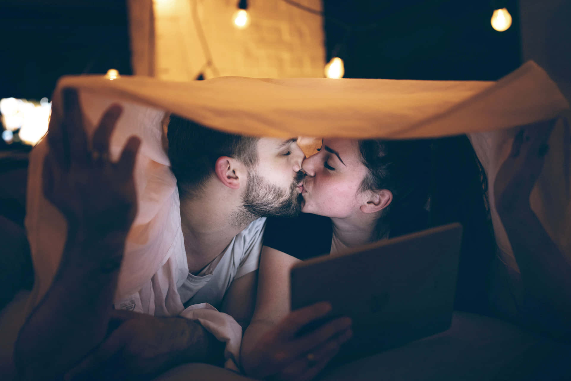 情侶在毯子下與串燈在夜晚接吻