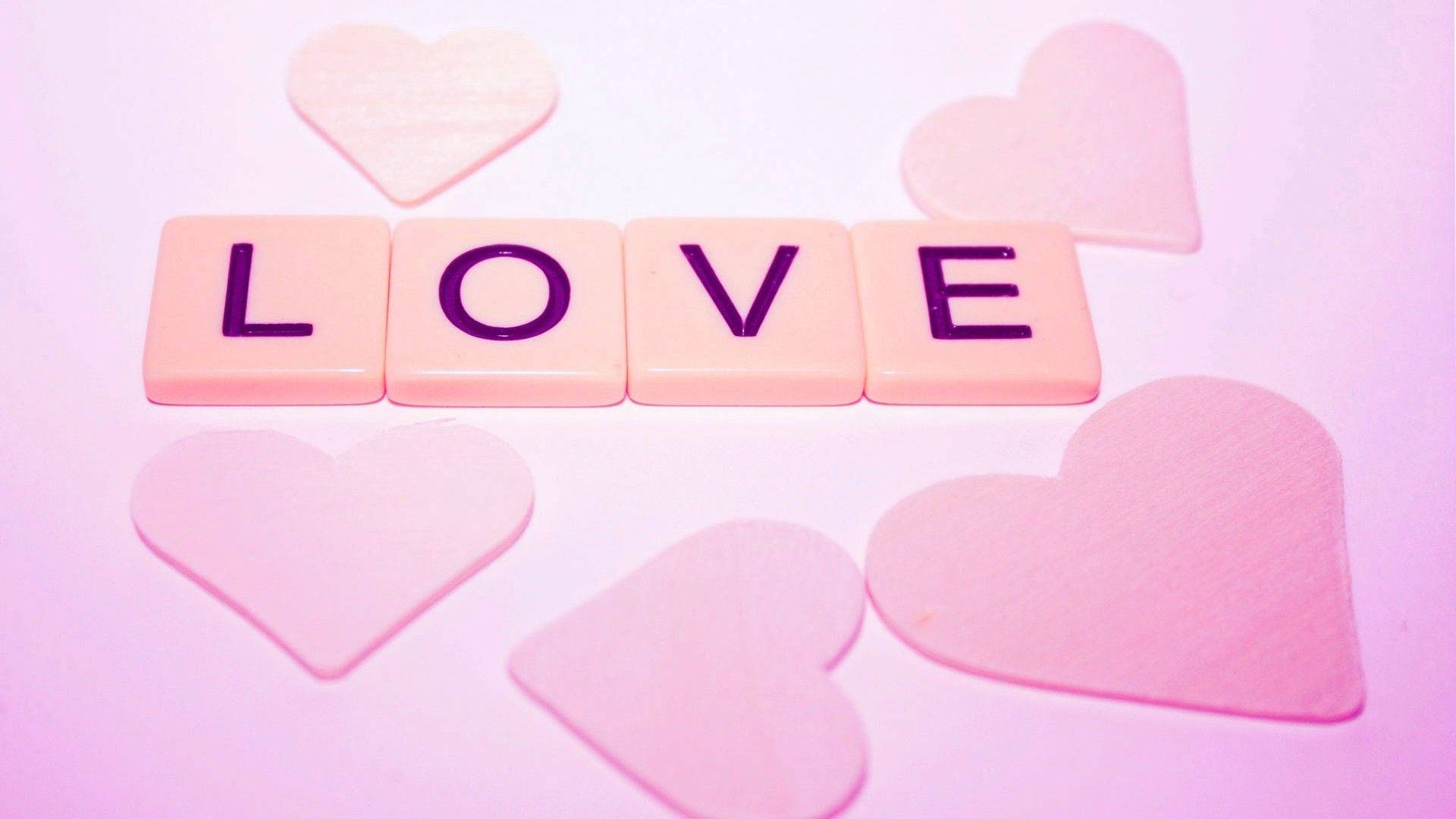 粉紅色瓷磚拼出 LOVE，散落的心形圖案在粉彩背景上。