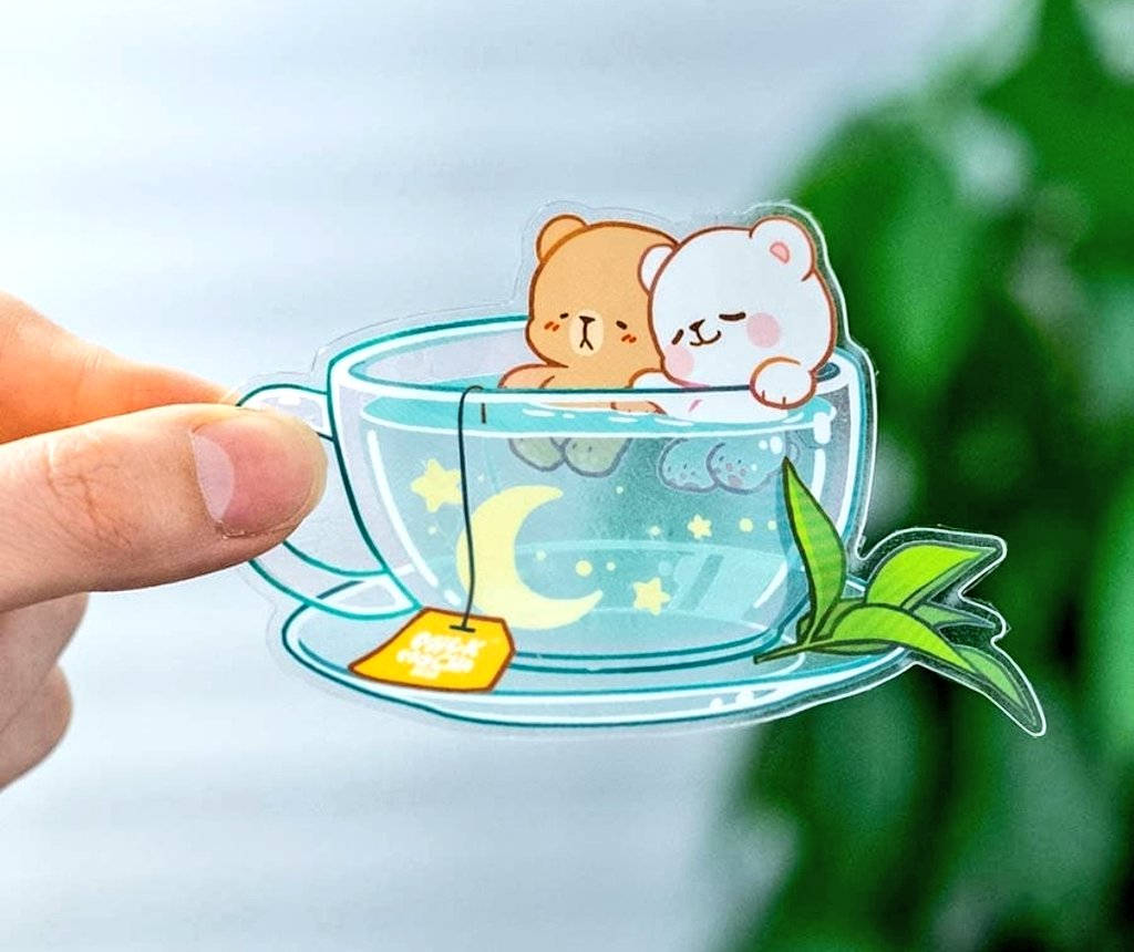 兩隻卡通熊在茶杯裡依偎，茶杯上有茶葉和月亮、星星。