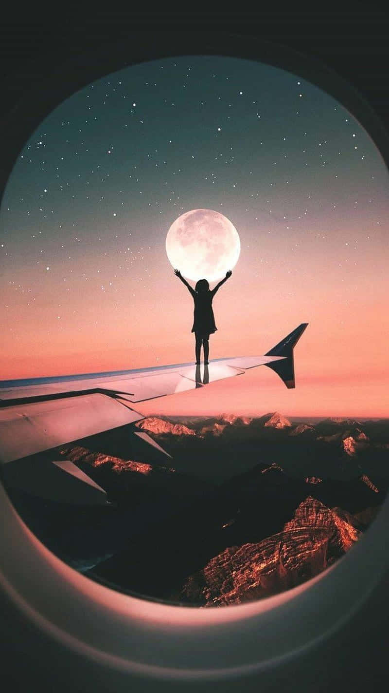 人站在飛機機翼上在暮色中伸手觸摸月亮