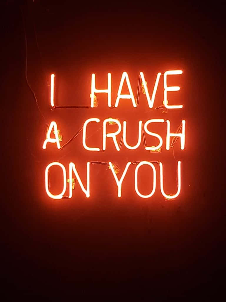 可愛發光鎖屏 壁紙 — 一個發光的橙色霓虹燈牌，上面寫著「I HAVE A CRUSH ON YOU」，背景是深色牆壁。