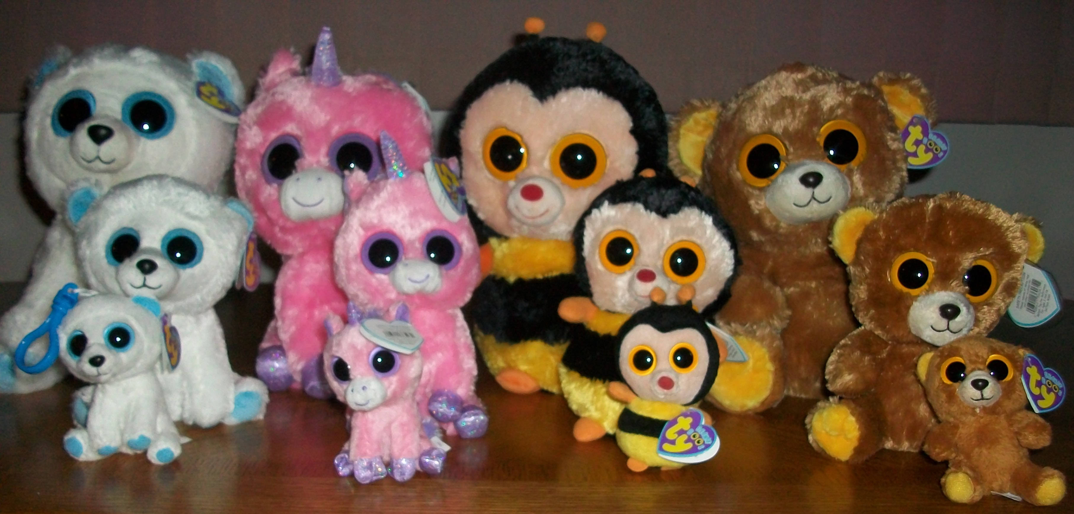 可愛的Beanie Boos絨毛玩偶集合 壁紙 — 色彩繽紛的Ty Beanie Boo毛絨玩具系列，包括熊、獨角獸和企鵝，排列在木質表面上。