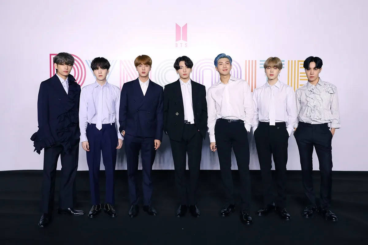 可愛的BTS成員同台演出 壁紙 — 七位時尚男士身穿正式西裝，在色彩繽紛幾何圖案的品牌活動背景前自信擺姿勢。