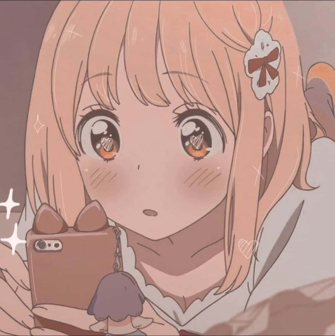 可愛的動漫女孩戴貓耳 壁紙 — 一個可愛的動漫女孩，桃色頭髮和心形眼睛，拿著一個帶有貓耳手機殼和小毛絨吊飾的手機。