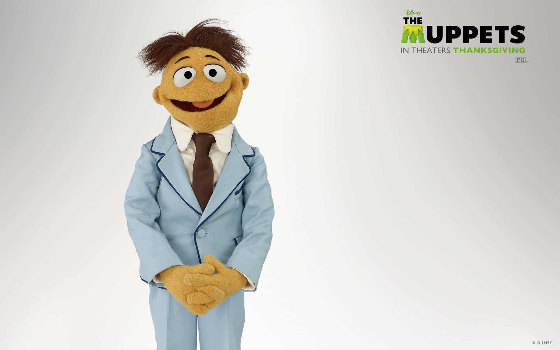 Muppet角色身穿藍色西裝和棕色領帶，對著鏡頭微笑。