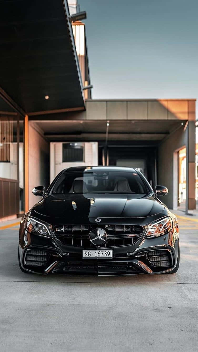 日落時黑色Mercedes-AMG停放在現代建築結構下。