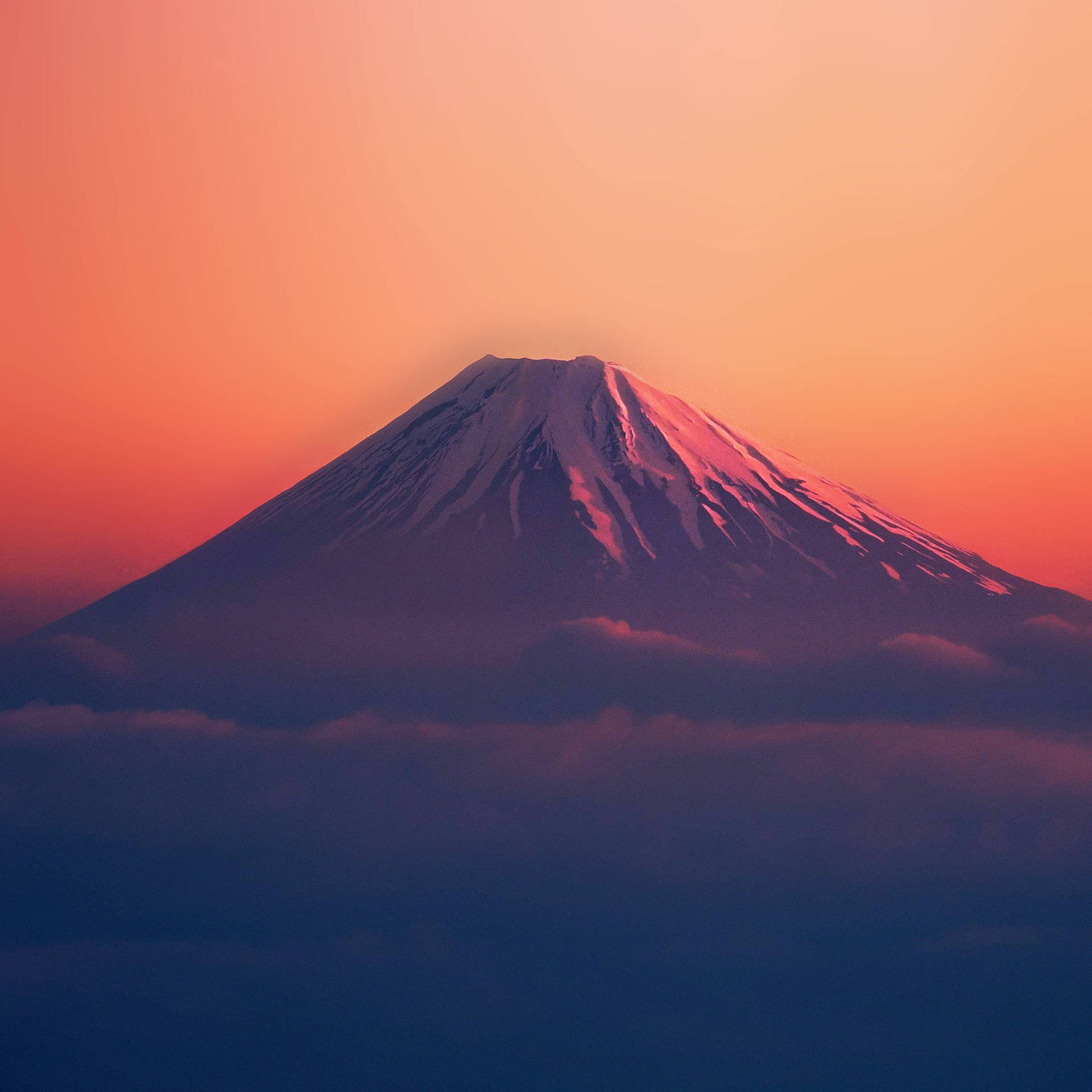 富士山在日落時分聳立於雲層之上，天空呈現橙色和粉紅色