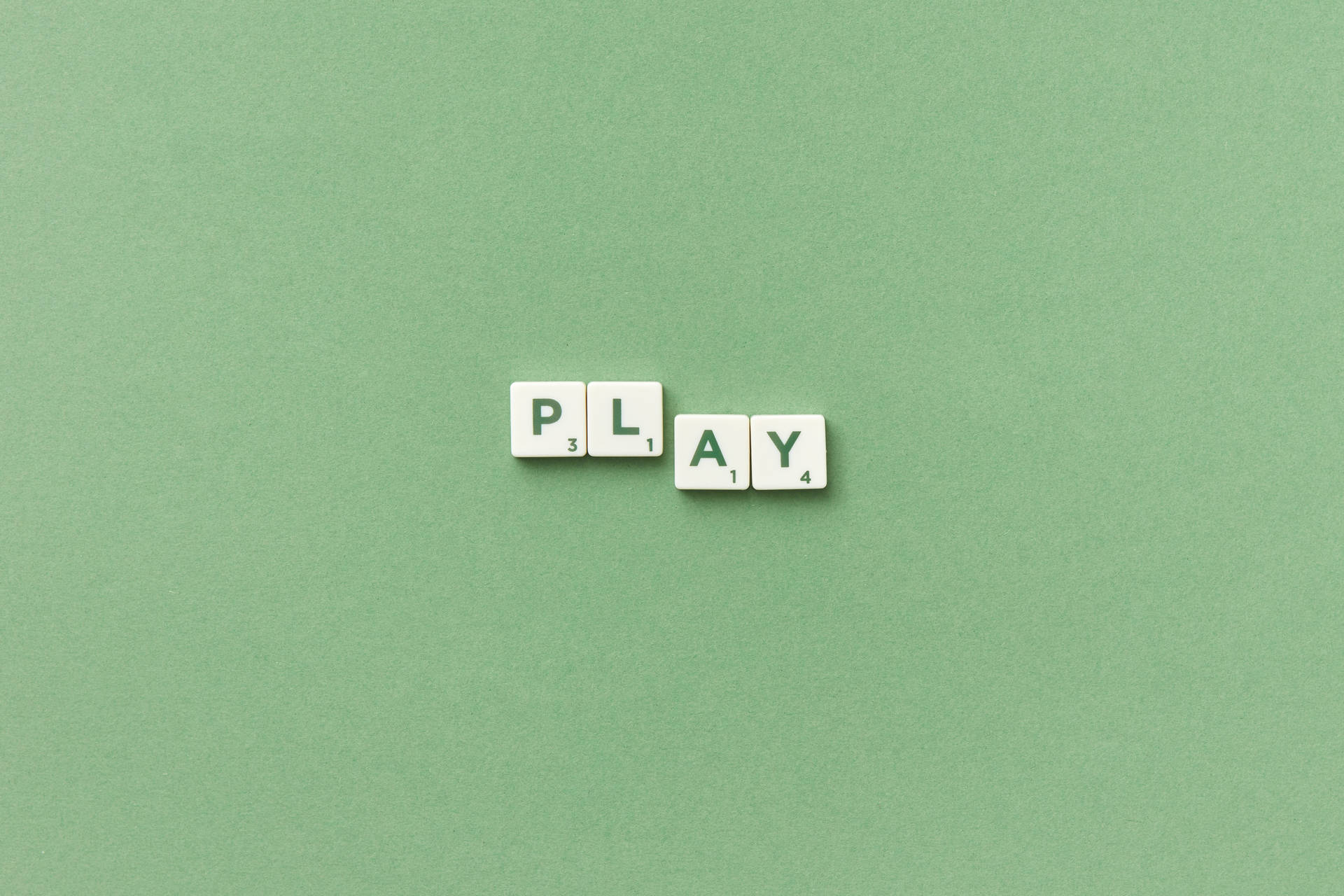 白色 Scrabble 字母磚在綠色背景上拼出 play