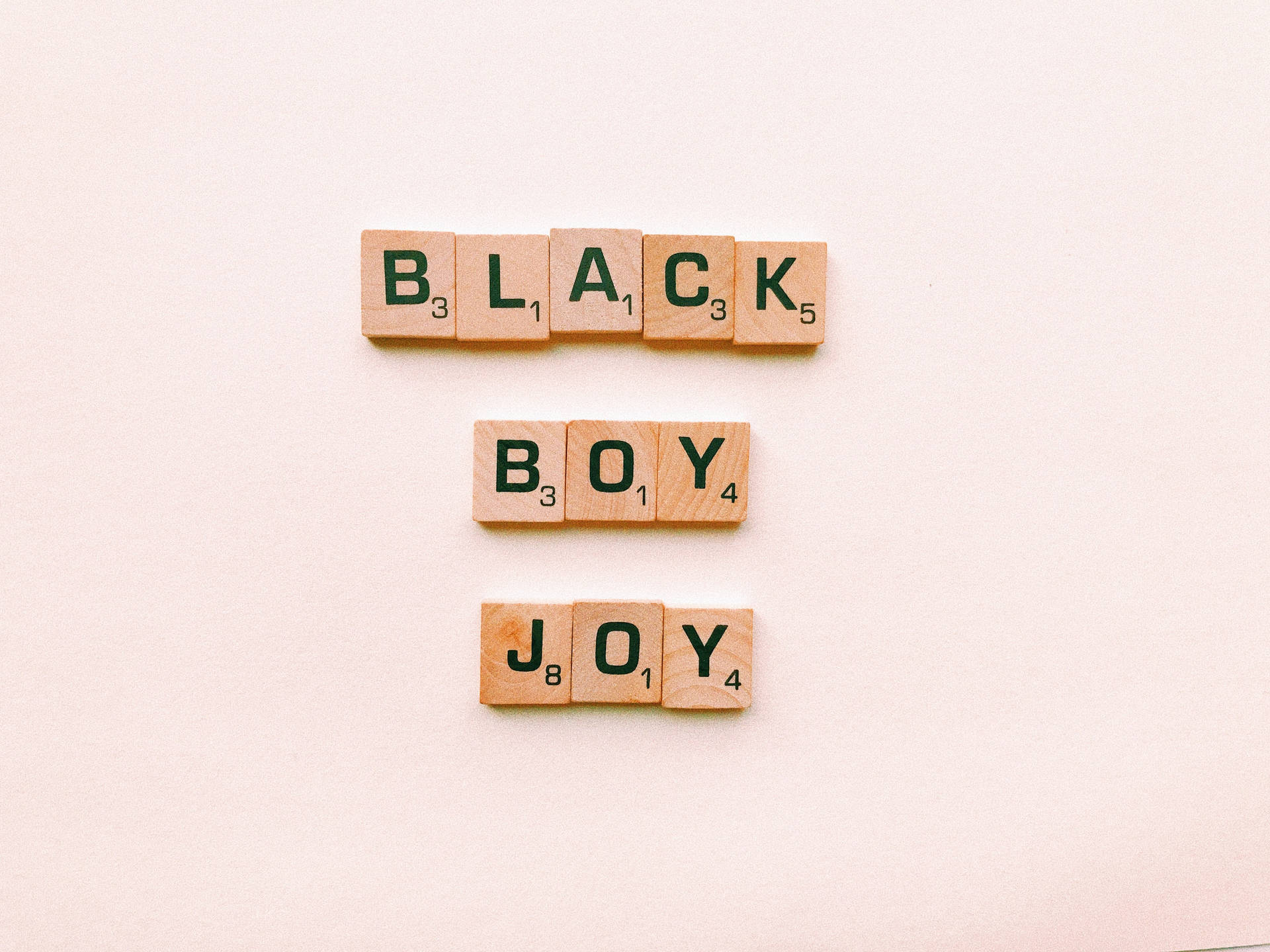 Scrabble 字母磚排列在米色表面上拼出「Black Boy Joy」。