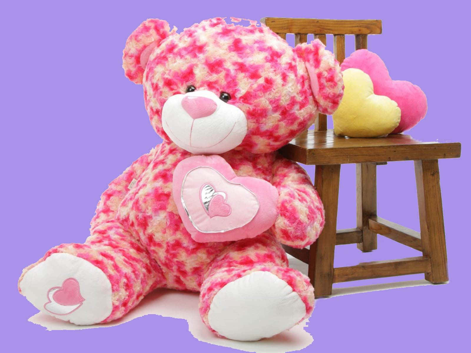 粉紅色泰迪熊抱著心形枕頭，旁邊是帶有心形坐墊的木椅。