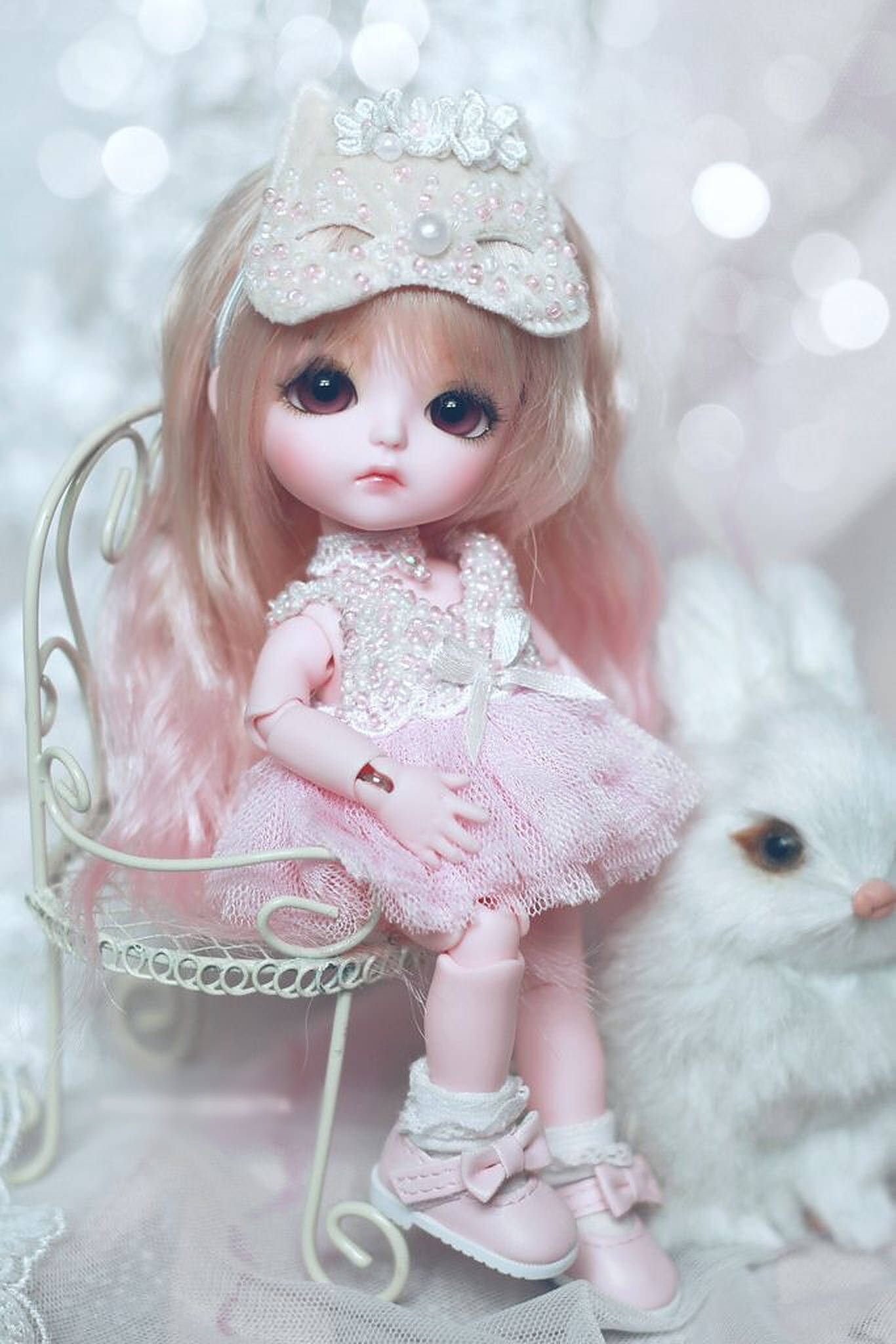 可愛迷你娃娃 壁紙 — 一個精緻的粉紅色 Blythe 娃娃，戴著珍珠裝飾的皇冠，坐在白色椅子上，旁邊有一隻毛茸茸的白色兔子，背景是閃爍的散景。