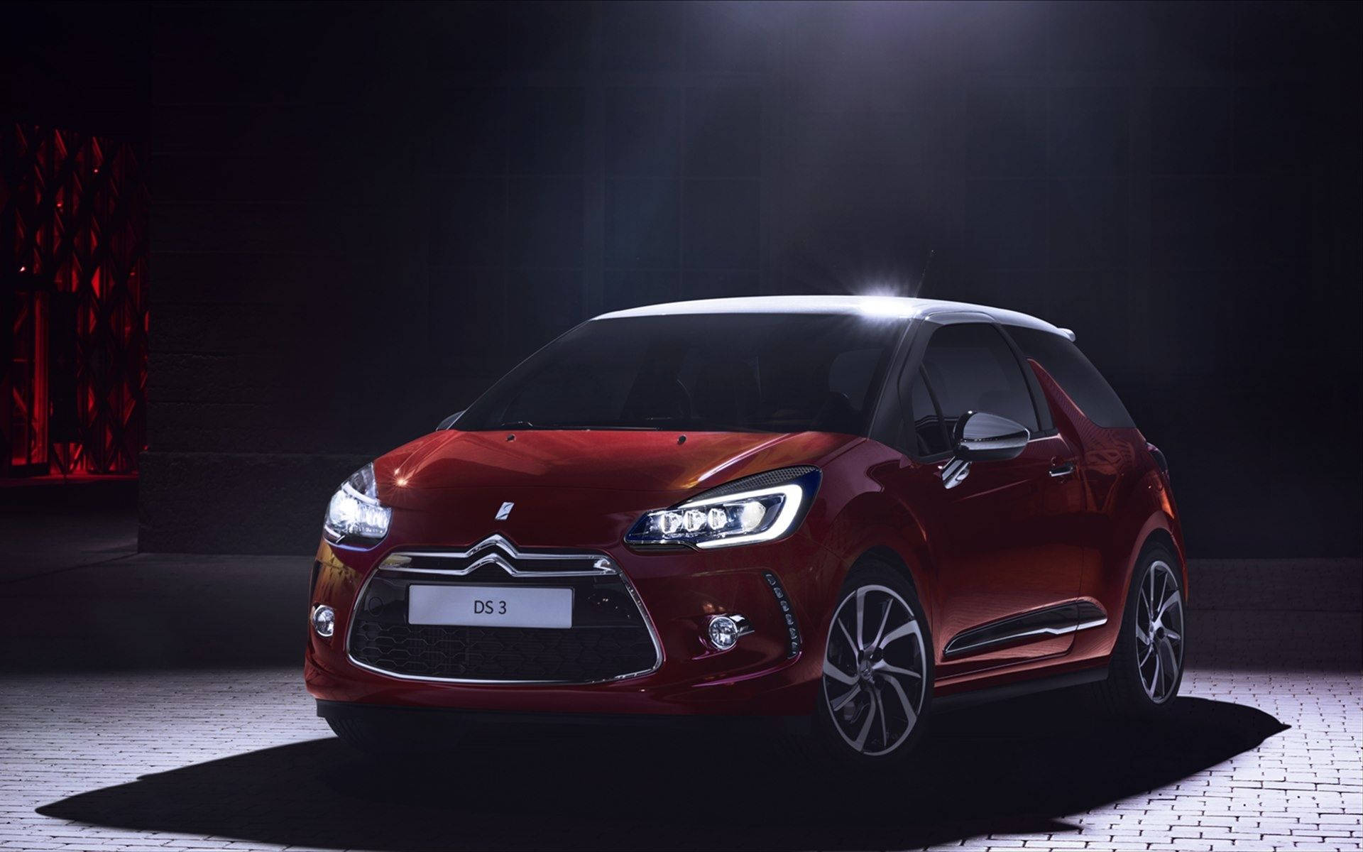紅色 DS 3 汽車在黑暗的攝影棚中被聚光燈照亮。