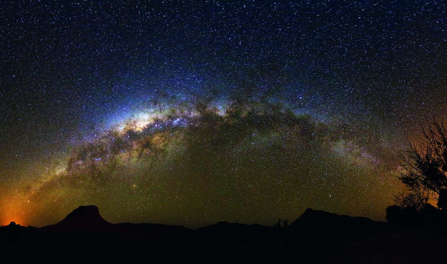 銀河系在星空下拱起於沙漠景觀之上