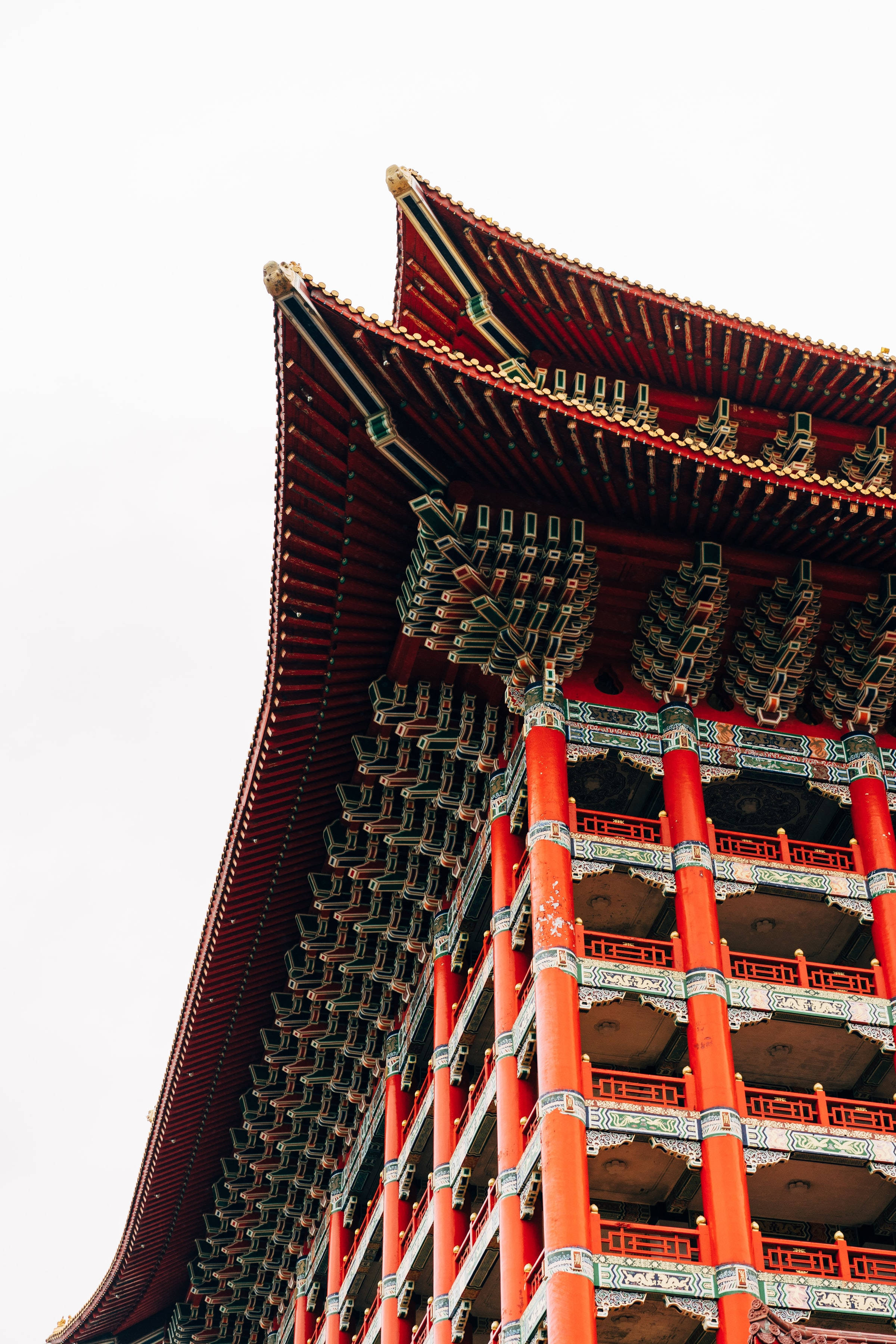 台北經典大飯店的壯麗風景 壁紙 — 從低角度觀看傳統中式寶塔，鮮紅色的柱子和華麗的彎曲屋頂瓦片映襯著蒼白的天空。
