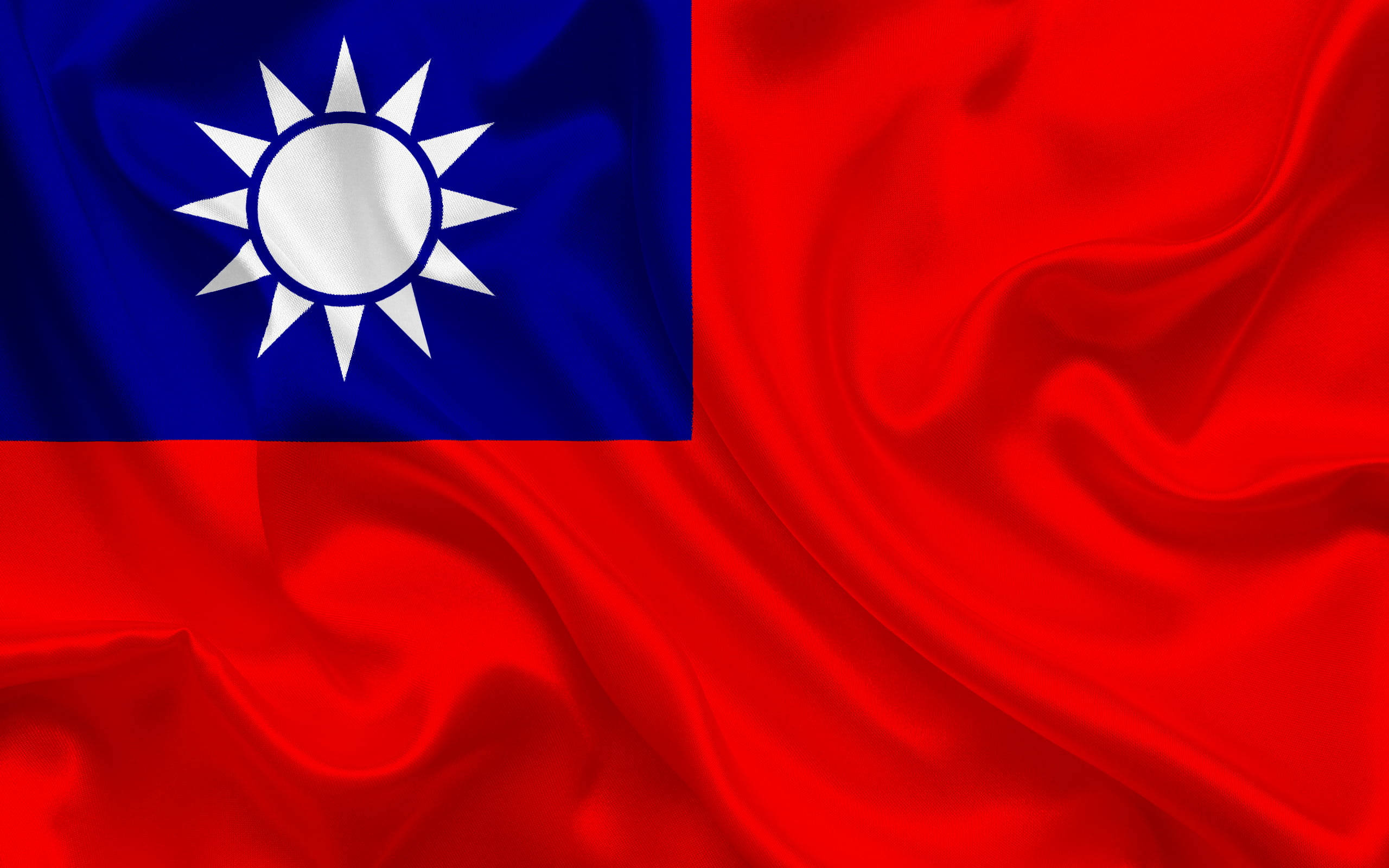 台灣國旗 壁紙 — 台灣國旗的近距離特寫，旗幟飄揚，紅色布料濃郁，藍色 canton 上有一顆白色太陽。
