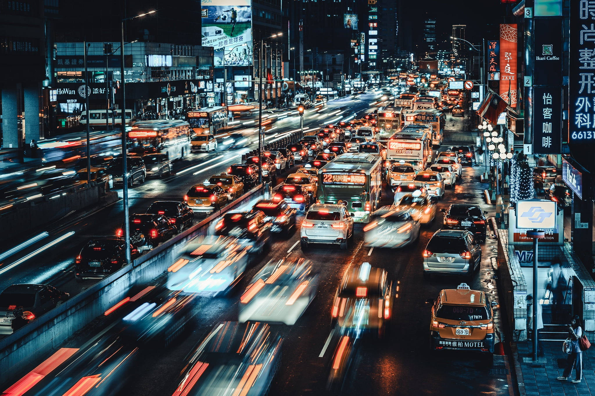 台灣夜間繁忙交通 壁紙 — 一條繁華嘅霓虹燈街道夜景，長曝光攝影捕捉到汽車燈光嘅軌跡。
