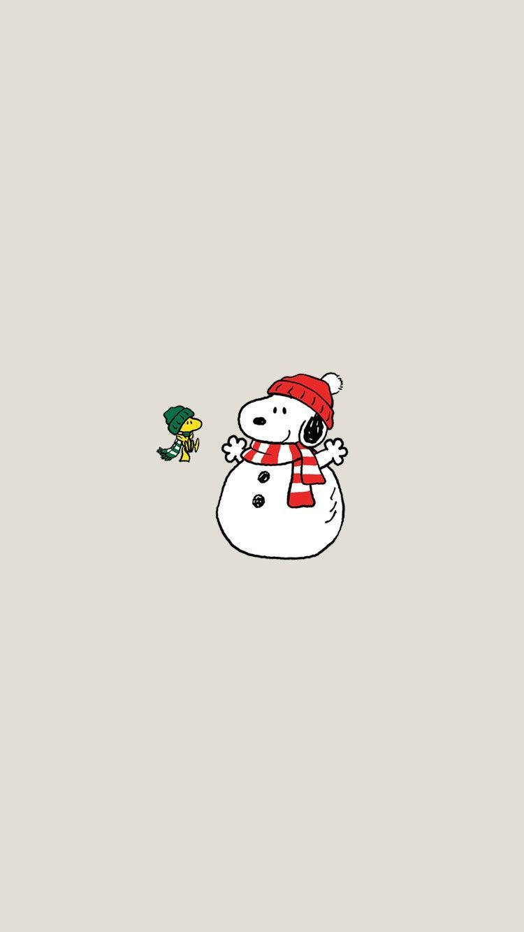 史努比聖誕雪人 壁紙 — 史努比打扮成雪人，戴著紅色帽子和圍巾，站在一隻戴著綠色帽子的小鳥旁邊，背景是米色。